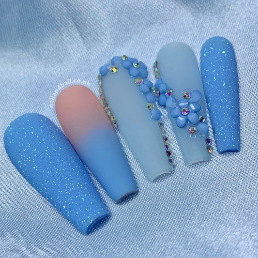 Introducing Spring Bling, the perfect accessory to elevate your look this season! These gorgeous press on nails feature a stunning combination of blue glitter, nail crystals, and blue 3D flowers. The nails are finished with a matte top coat for a modern and chic look that is sure to turn heads.