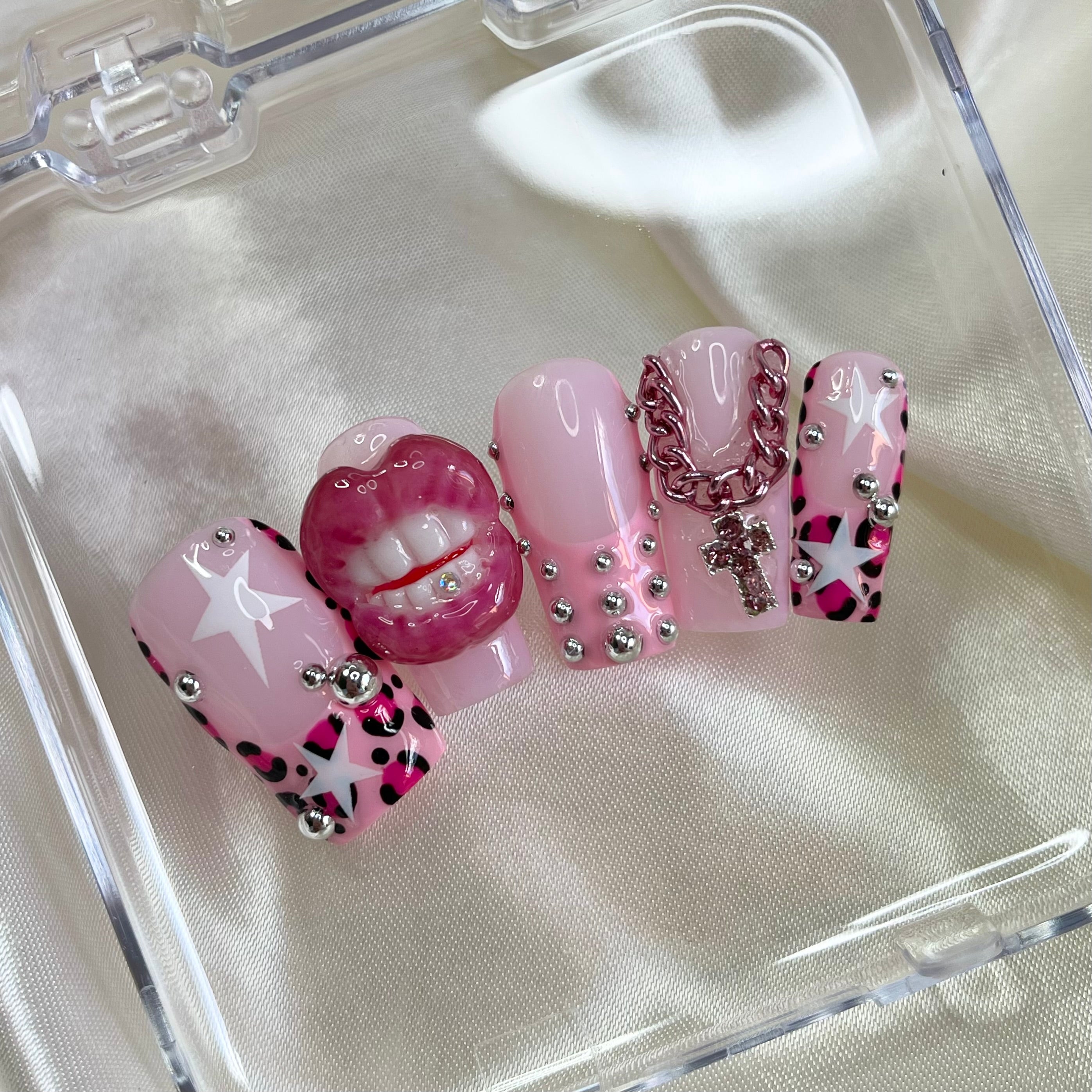 Juicy Baby is a Y2K baddie press-on nail set with 3D lips + tooth gem, cheetah French tips, pink cross charm, silver pearls, stars & glossy pearl accents.