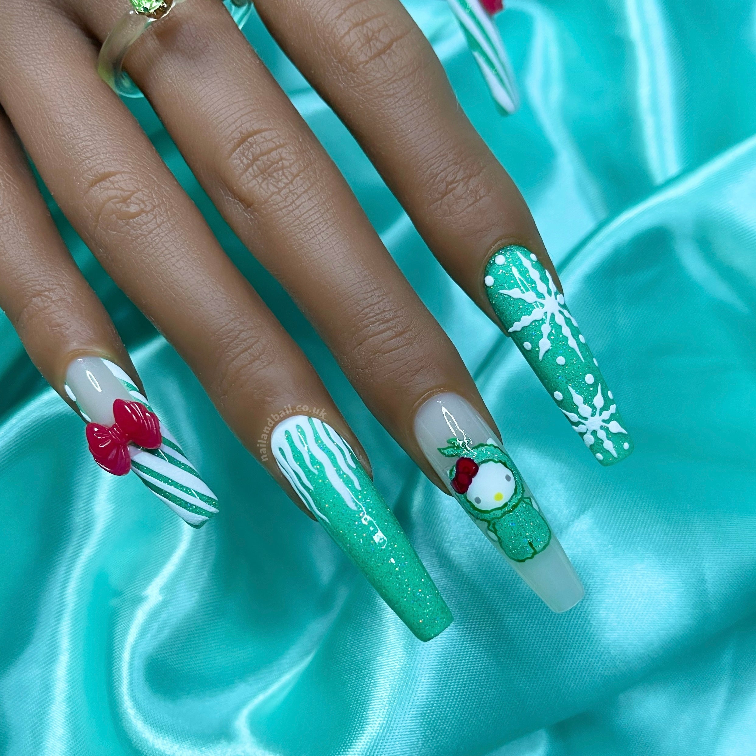 Meet "Whoville Kitty" press-on nails – where girly glam meets holiday cheer! Nude bases with glittery green French tips, adorned with candy cane stripes and red bow charms on thumbs and pinkies. Green glitter magic with snowflakes and icicles on pointer and ring fingers. The star? A hand-painted Hello Kitty as The Grinch on the middle finger. Elevate your festive style with this adorable nail set! 🎀✨
