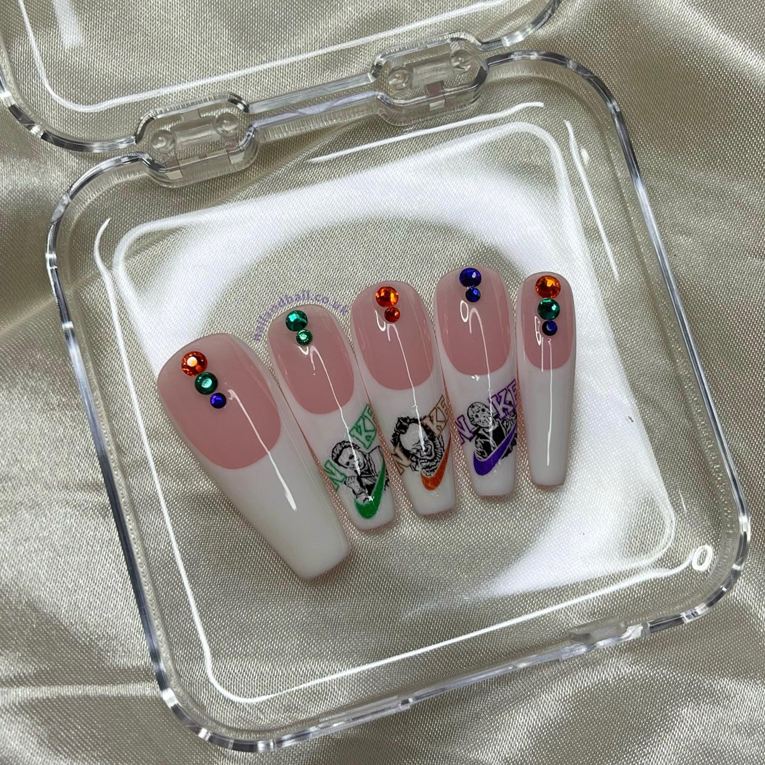 Unleash your bold side with “Just Kill It”. These press-on nails feature swoosh-inspired designs with horror character details and are accented with orange, purple, and green crystals. Perfect for adding an edgy, stylish touch to any look.