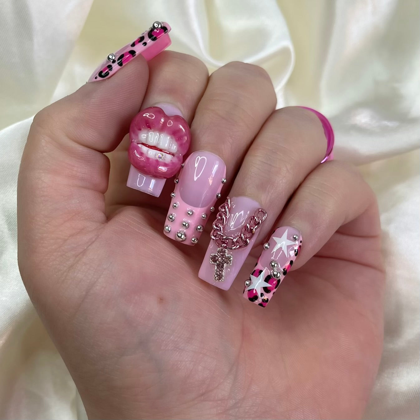 Juicy Baby is a Y2K baddie press-on nail set with 3D lips + tooth gem, cheetah French tips, pink cross charm, silver pearls, stars & glossy pearl accents.