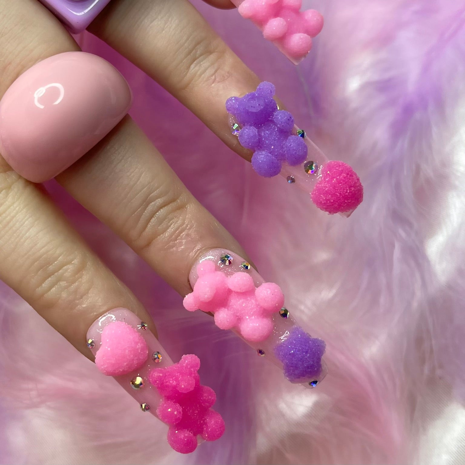Cute bear charm nail art on pale pink shimmer press-on nails with crystal details