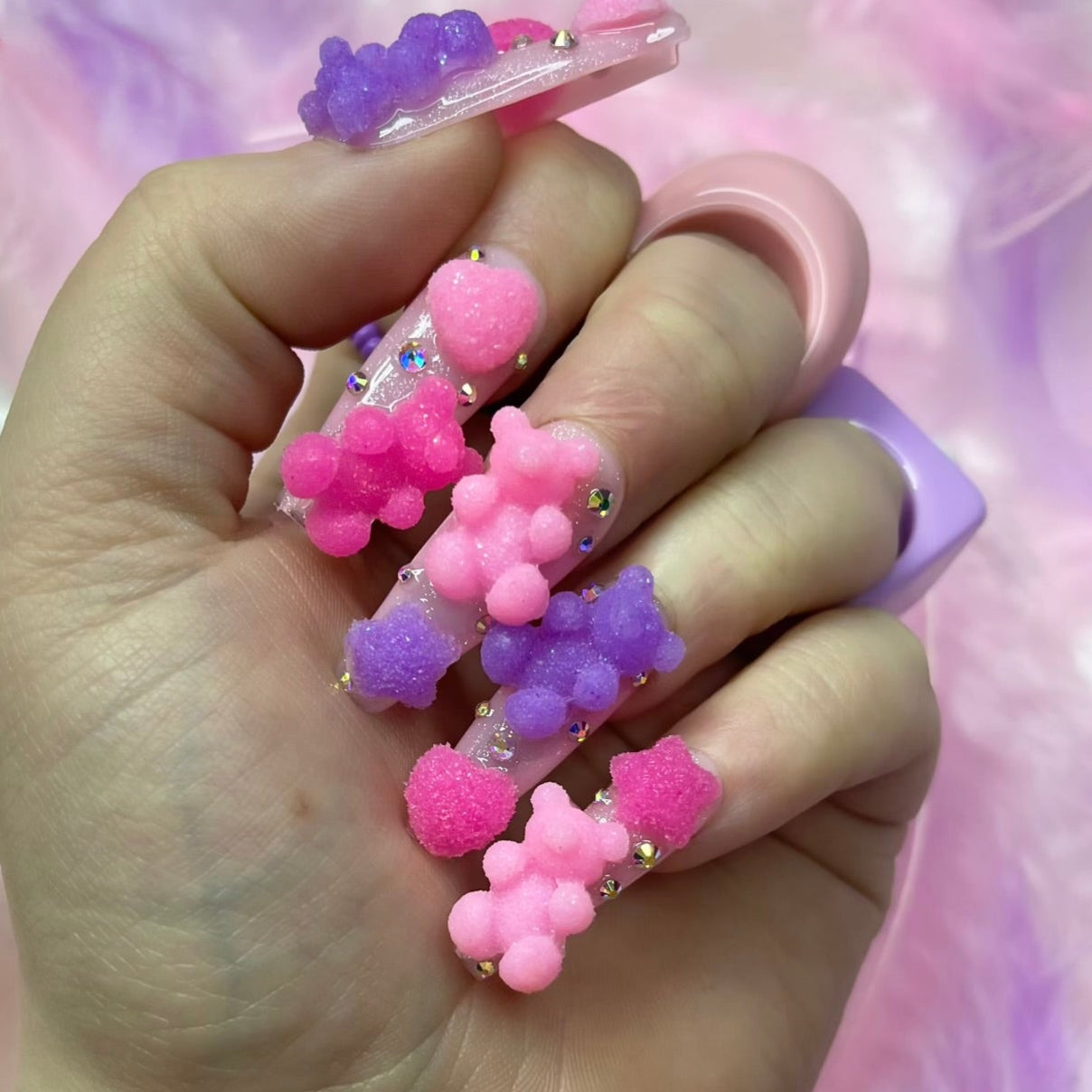 Pink shimmer press-on nails with bear charms, heart details, and silver crystal nail art