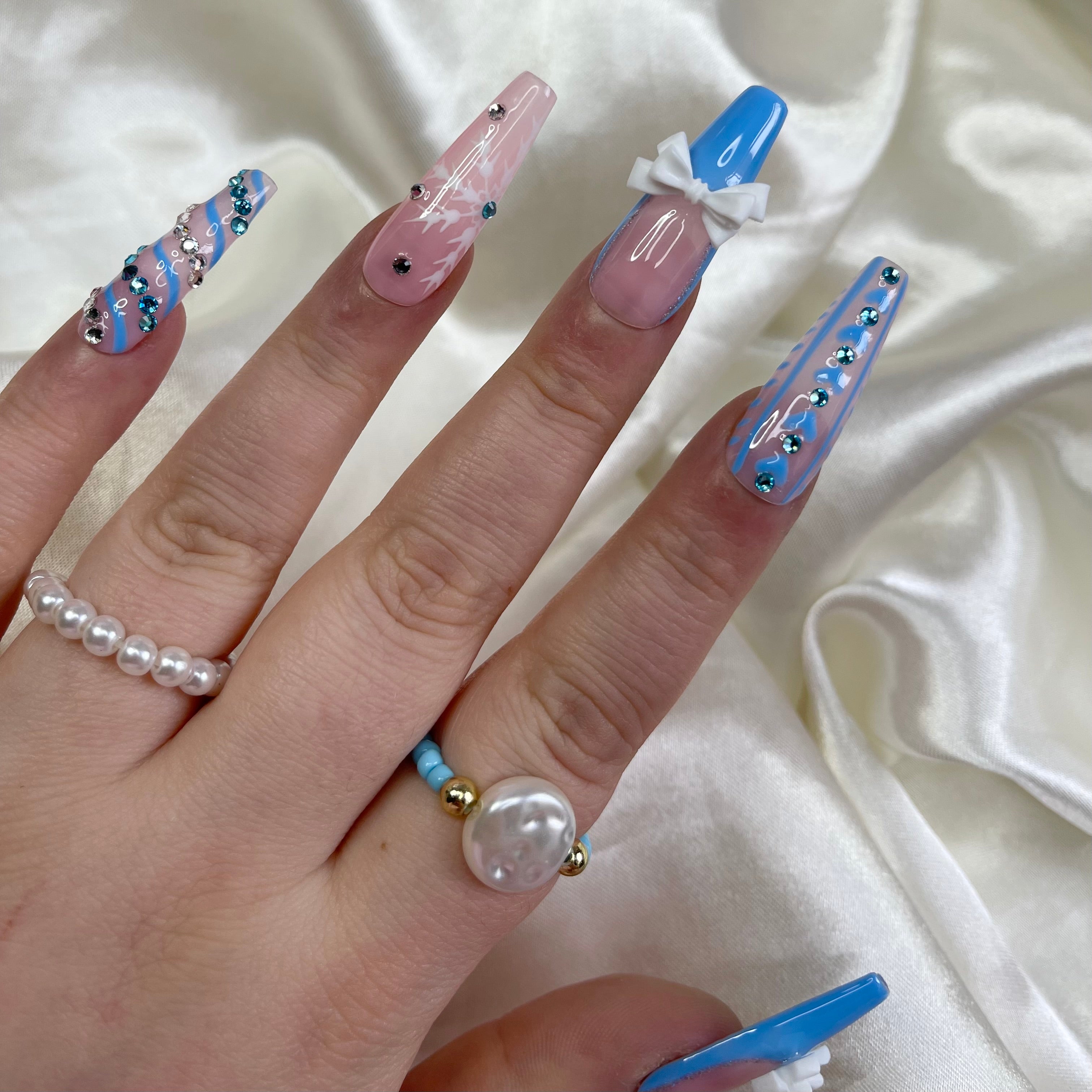 Blue French tip press-on nails with silver outlines and white bow nail art