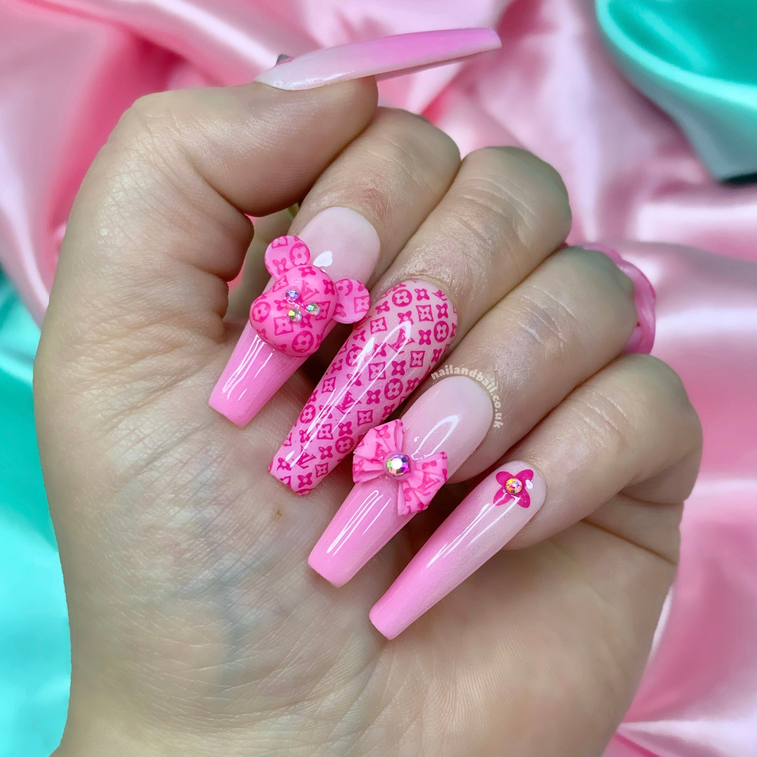 Pink ombré press-on nails with bear charms, bow nail art, and luxury-inspired details
