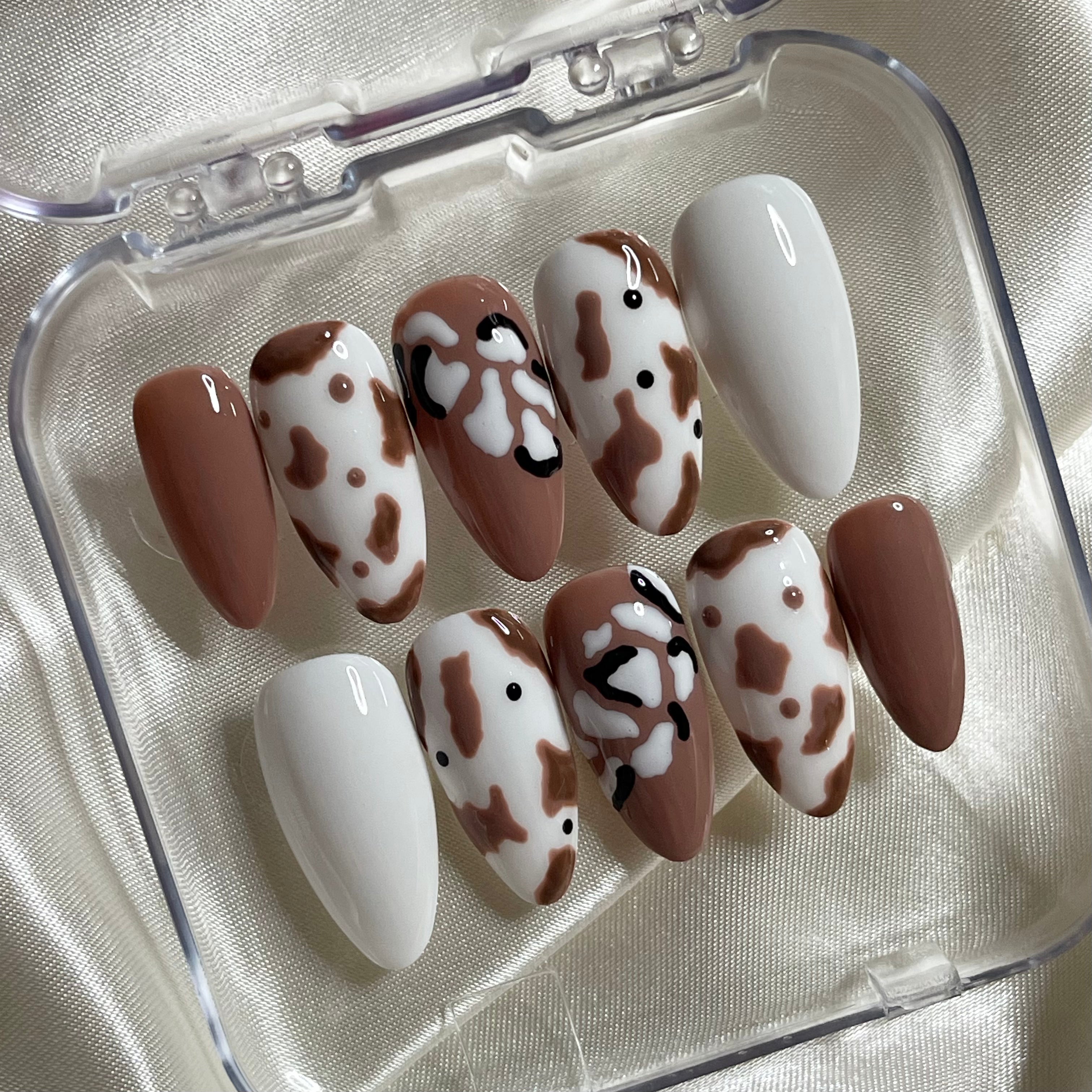 Hand-painted brown cow print press-on nails with chocolate brown and white accents
