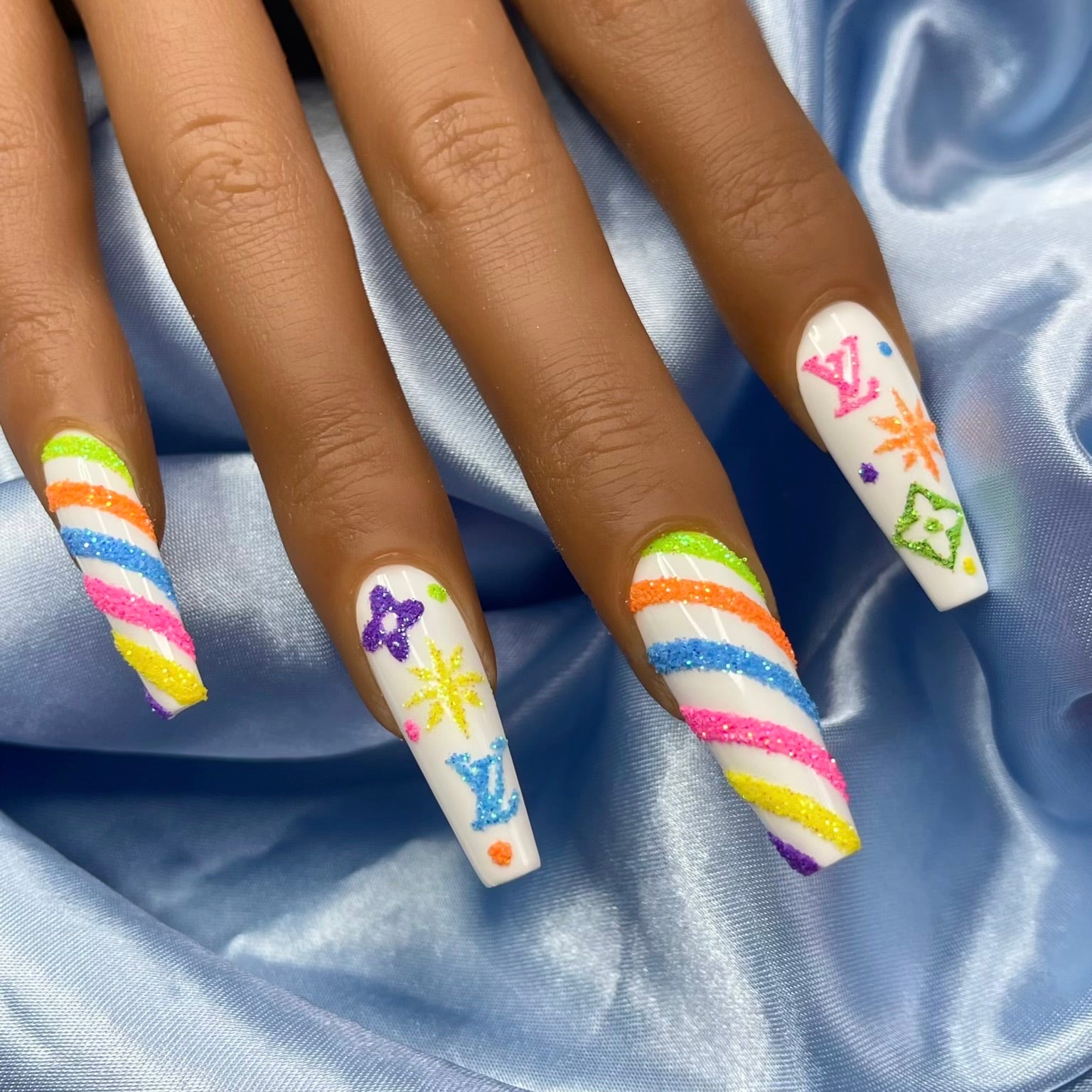 A set of nails painted with a candy cane and snowflake design, featuring multicolored stripes and decorations in a festive pattern.