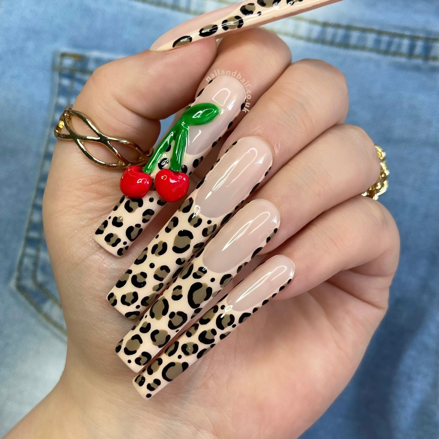 Y2K press-on nails with leopard print French tips and 3D cherry nail art