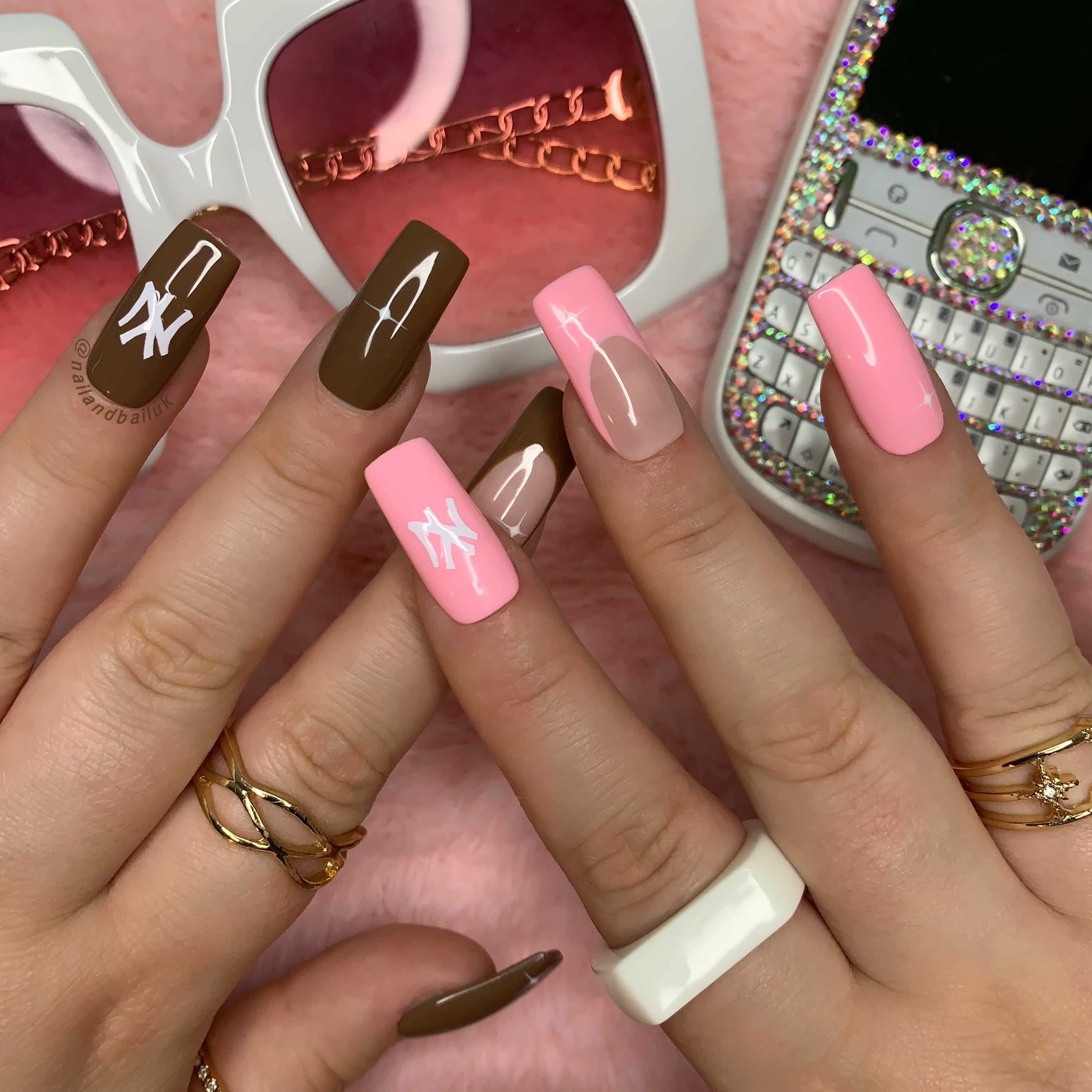 Nude press-on nails with pink and brown French tips, white stars, and New York Yankees-inspired nail art