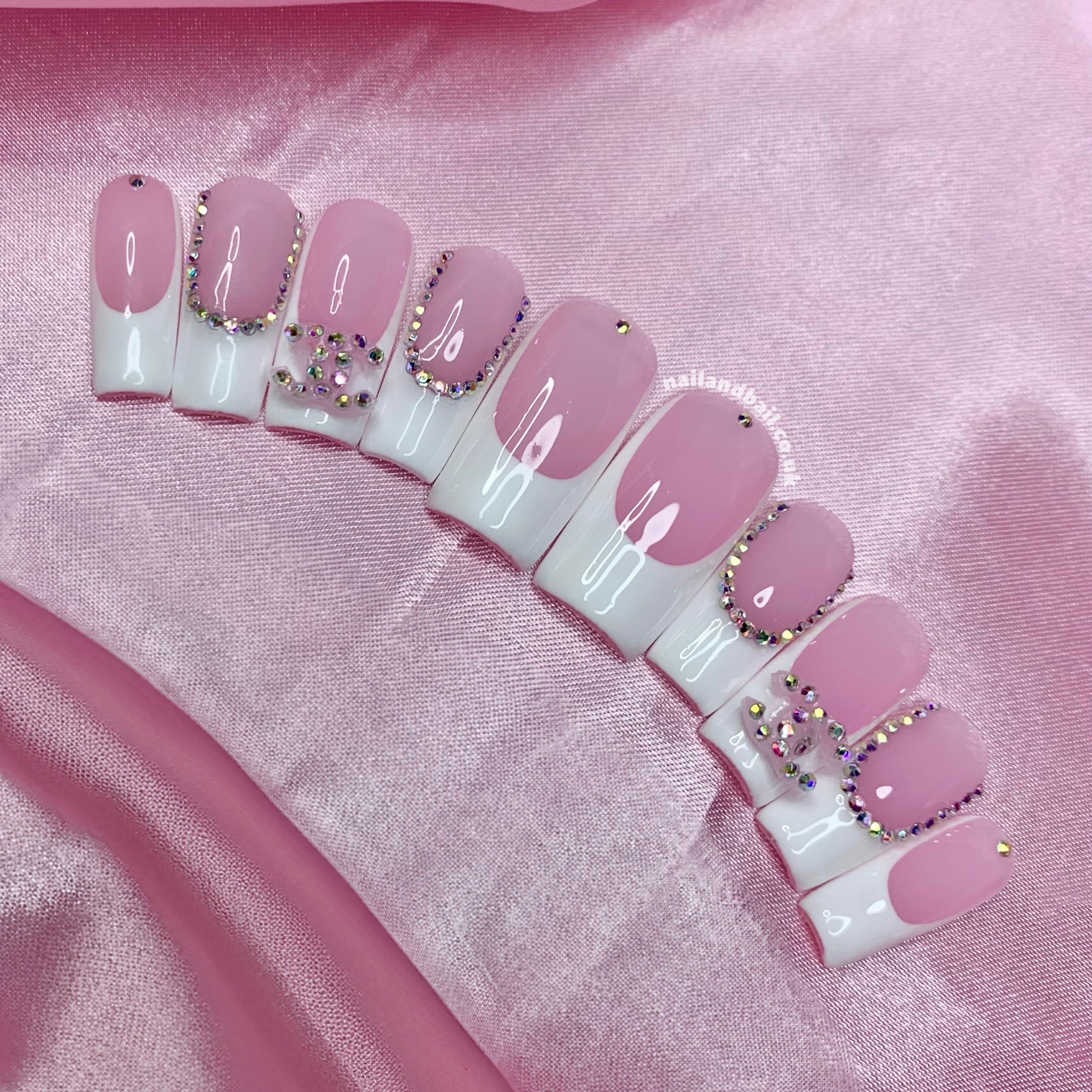 Pink and white French tip press-on nails with crystal charms and luxury nail art