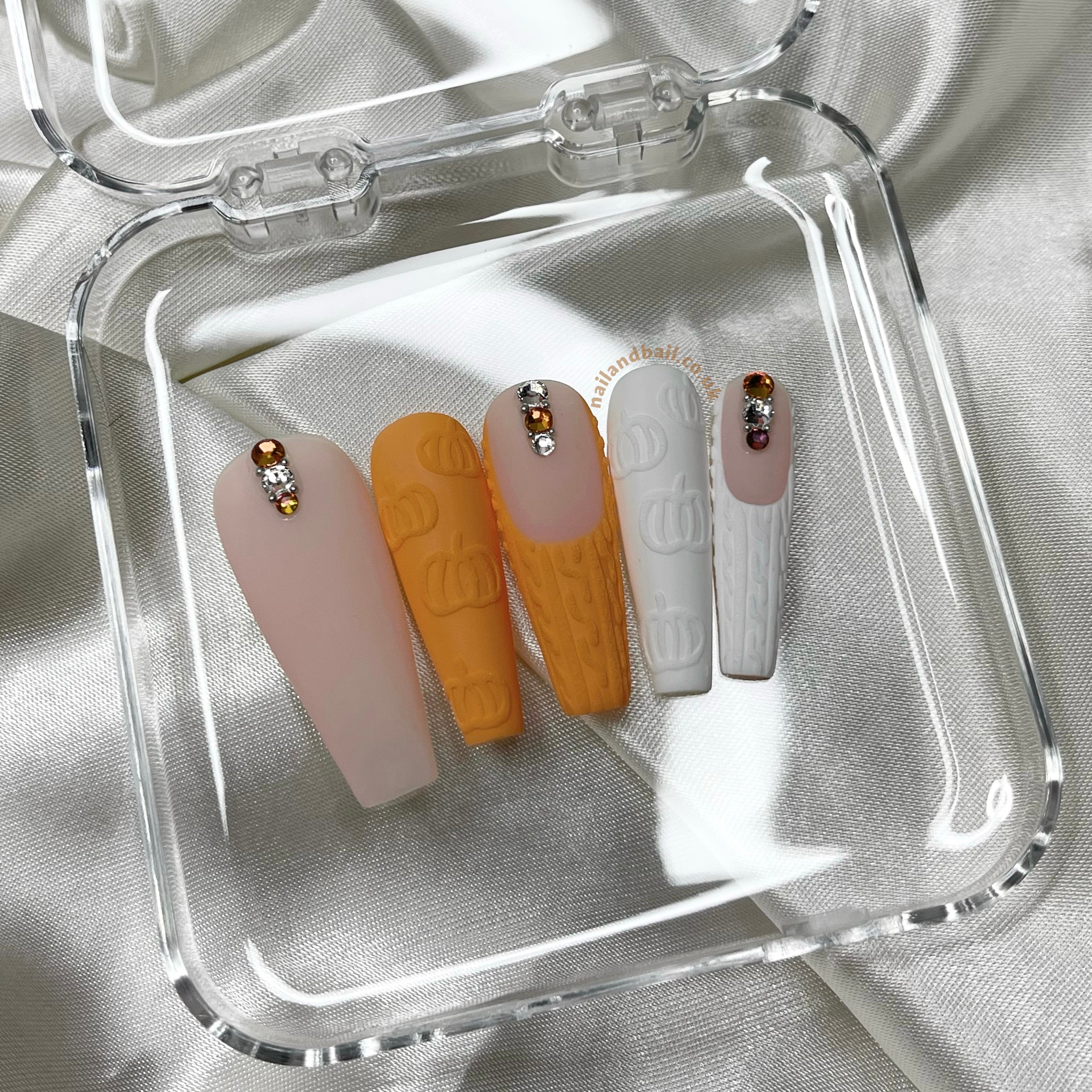 Autumn press-on nails with embossed pumpkin nail art, sweater details, and pastel orange tones