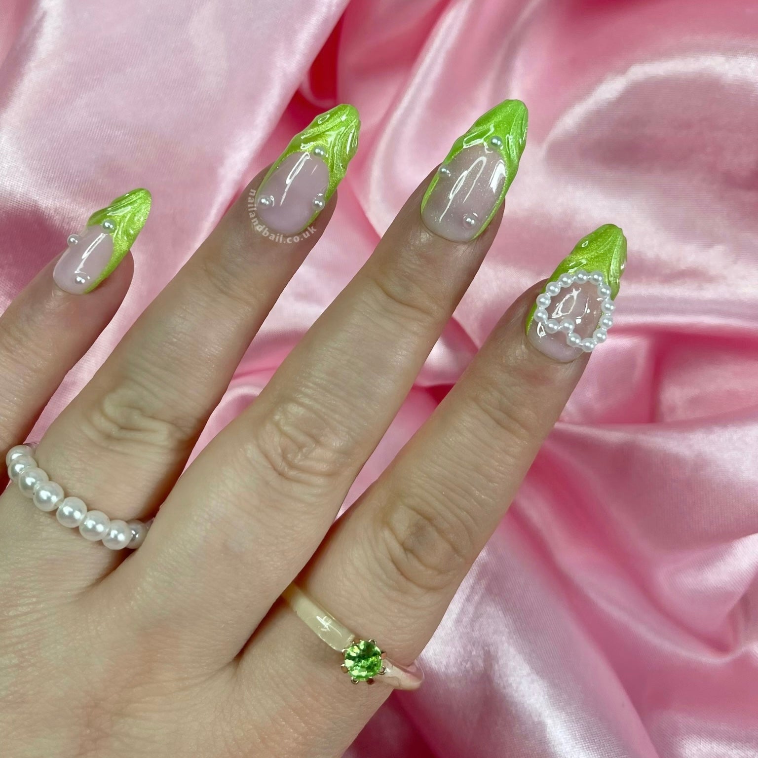 Green shimmer press-on nails with pearl details and heart charm nail art