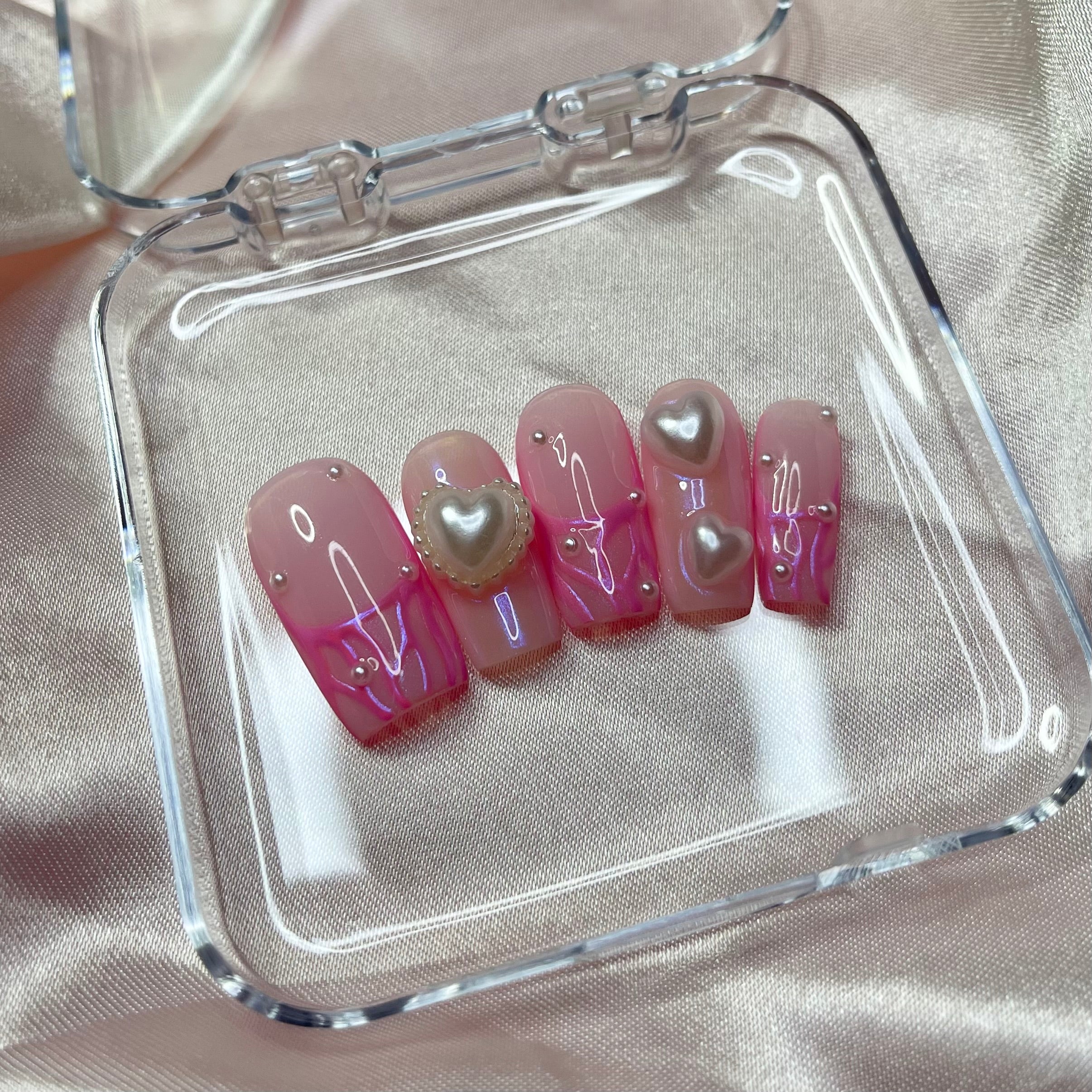 Glossy pink chrome press-on nails with pearl accents and heart nail art