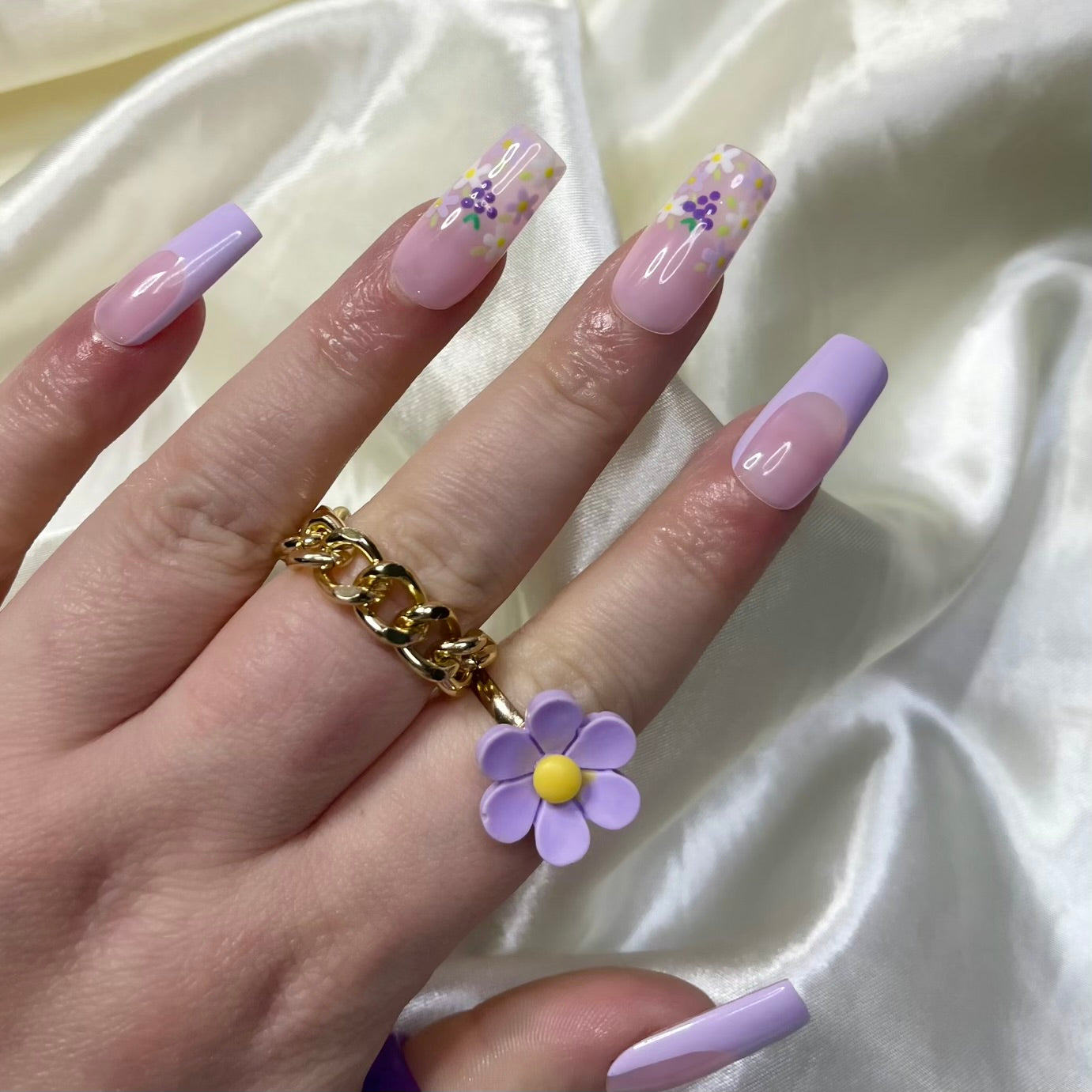 Grape Escape press-on nails with purple French tips, floral designs, hand-painted grapes, and pinky nude bases. Perfect for a fruity, spring-inspired look.