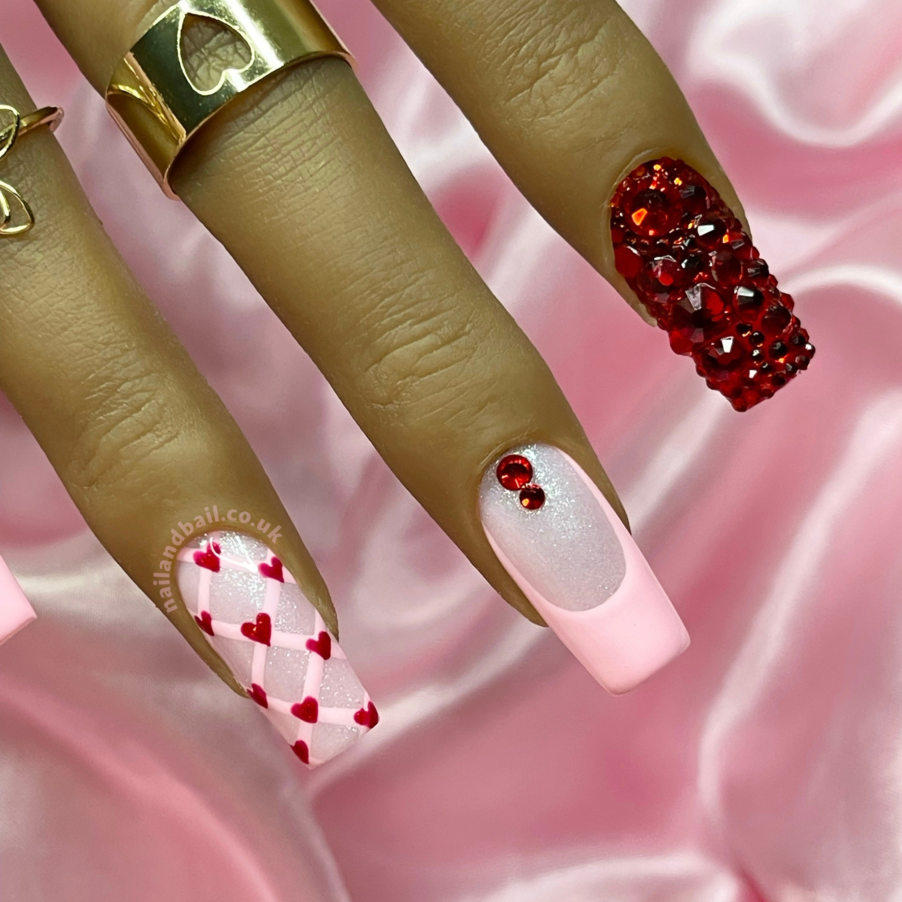 Red heart nail art on pink shimmer press-on nails with crystal details