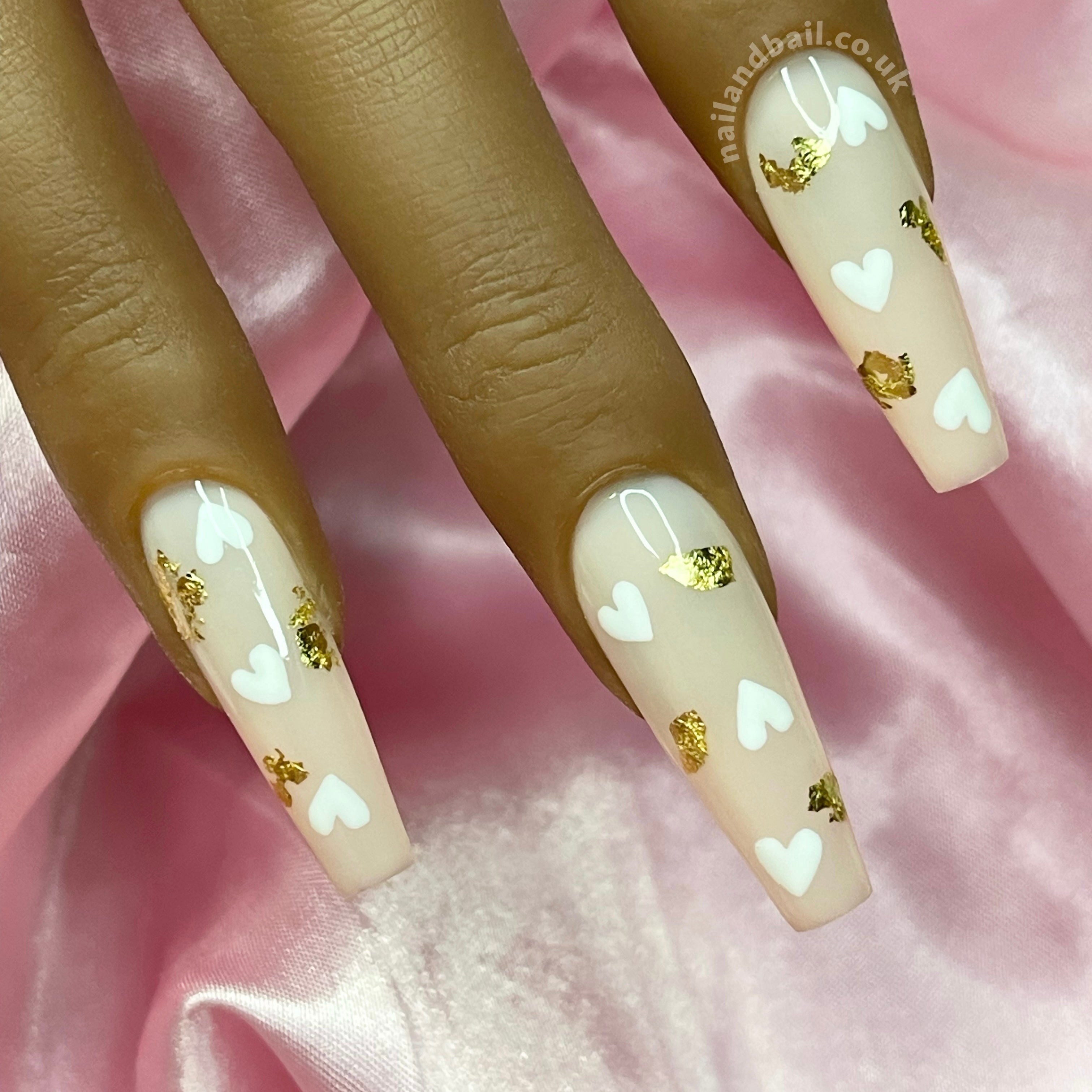 Nude press-on nails with white heart nail art and gold leaf details