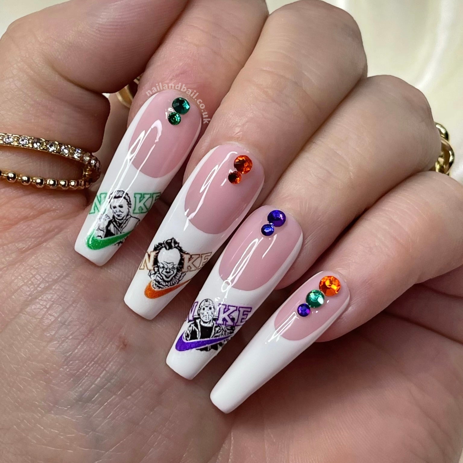 Horror-inspired press-on nails with swoosh-style nail art and colourful crystal details