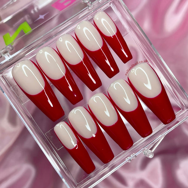 Nude press-on nails with hand-painted red French tips and glossy finish