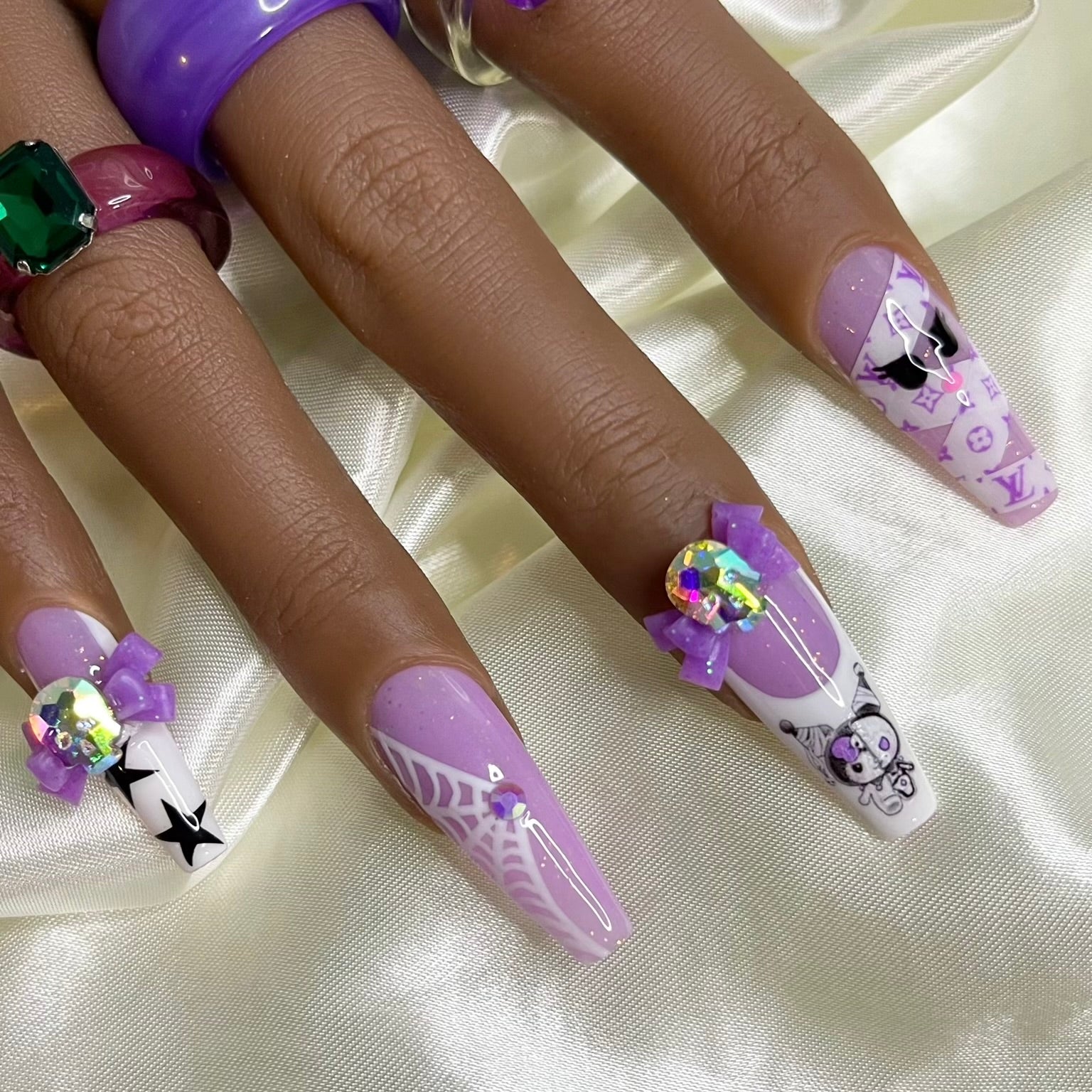 Close-up of purple glitter Kuromi-inspired press-on nails with crystals and spiderweb nail art