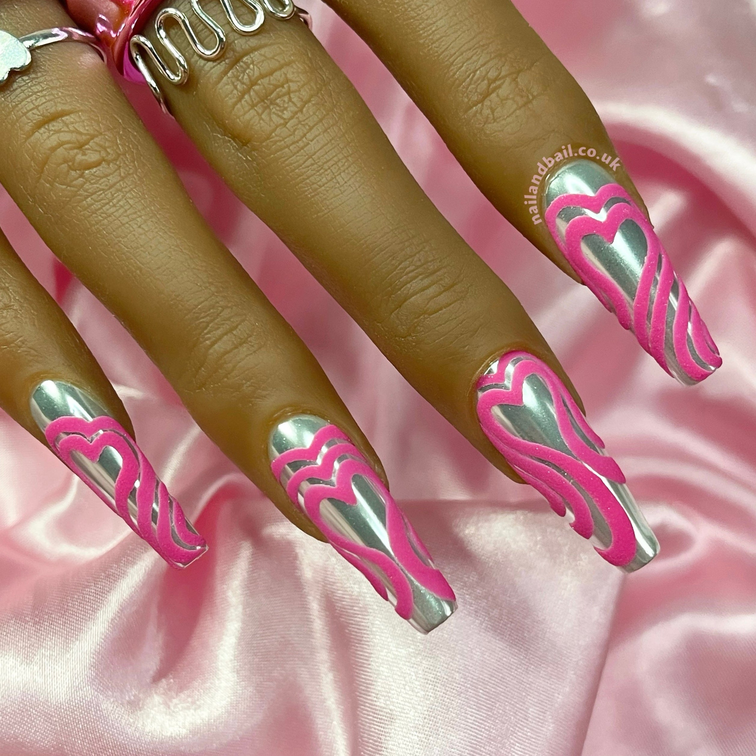 Silver chrome press-on nails with bright pink embossed heart nail art
