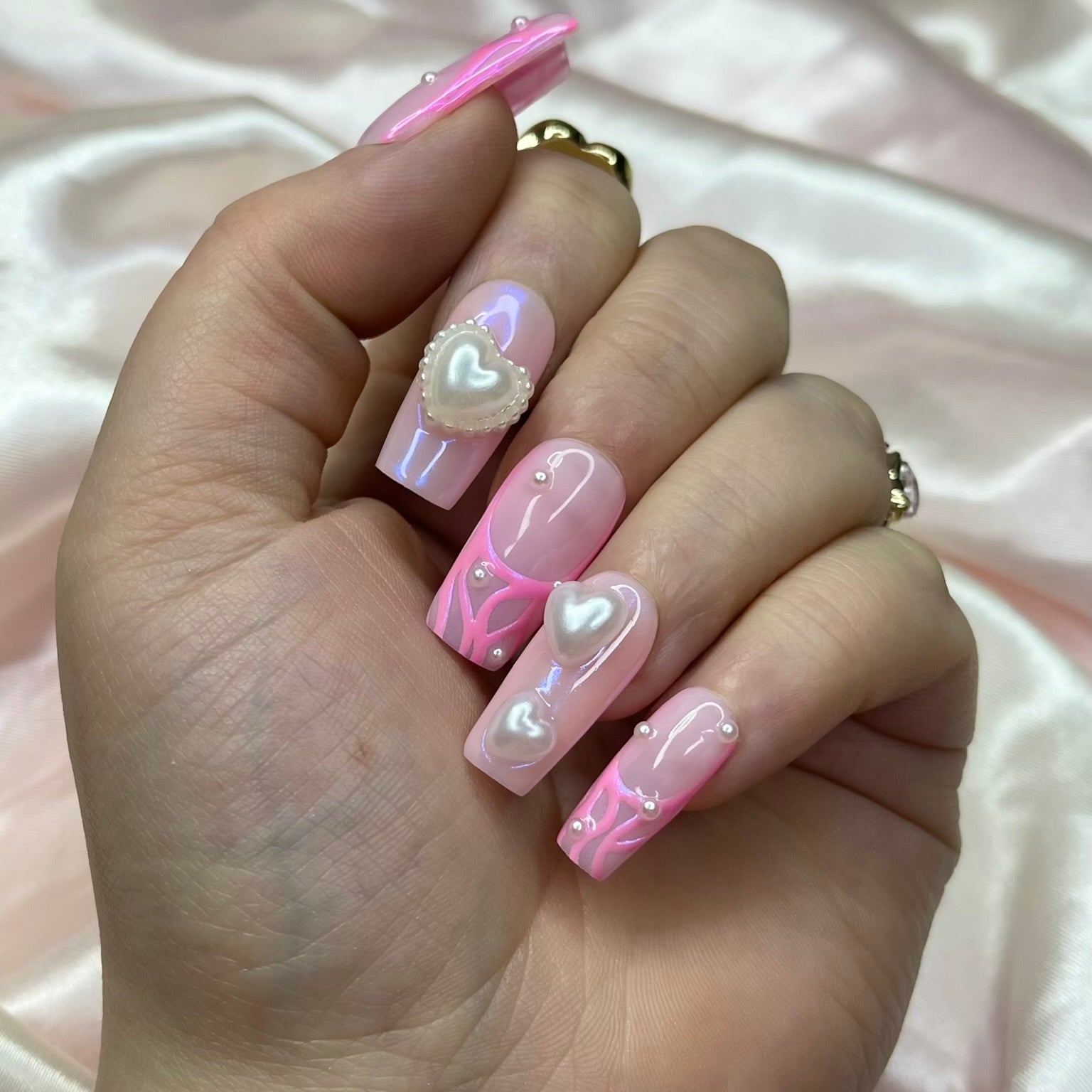 Luxury pink chrome press-on nails worn on hand with pearl heart nail charms