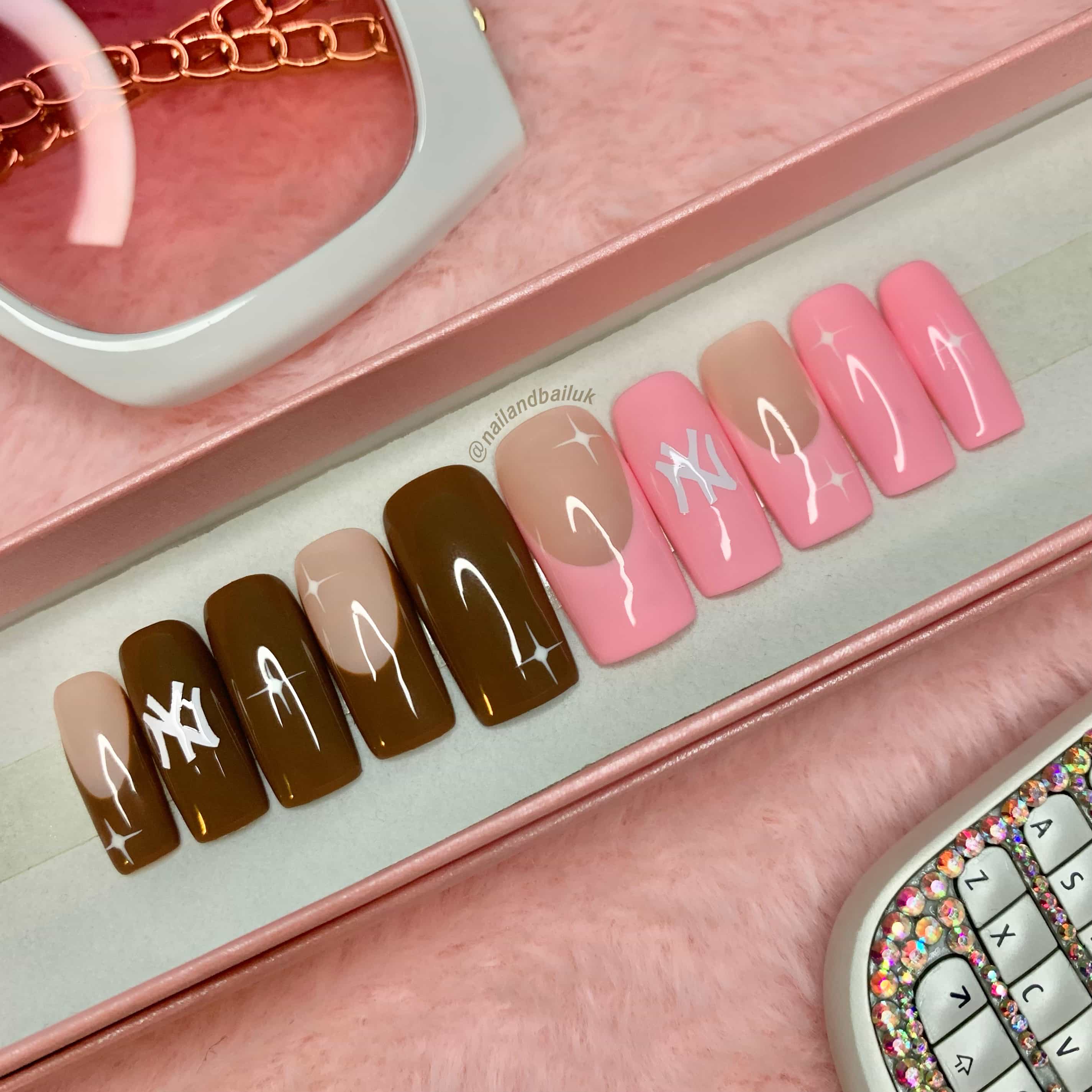 Pink and chocolate brown French tip press-on nails with sporty-inspired artwork and white stars