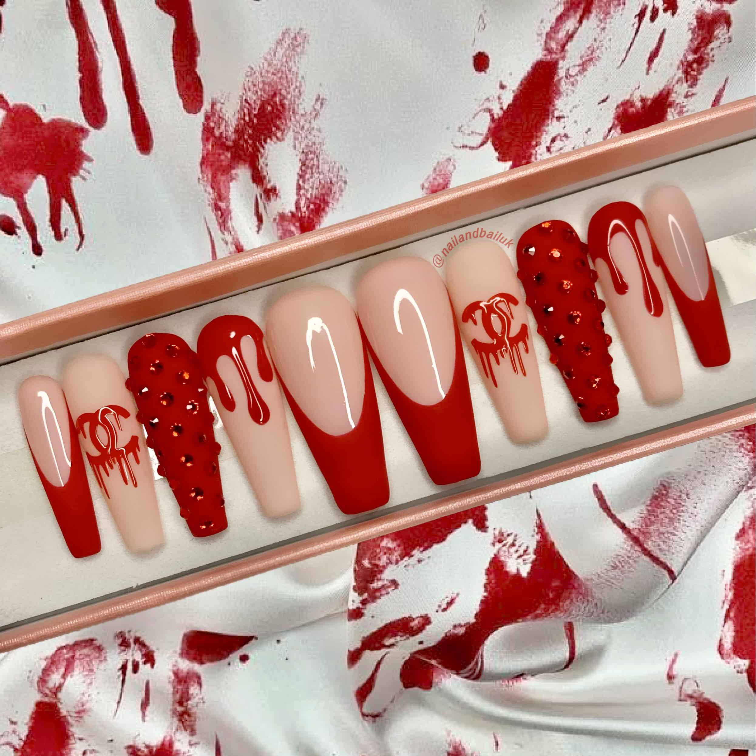 Matte red French tip press-on nails with sparkling crystal accents and luxury-inspired detailing