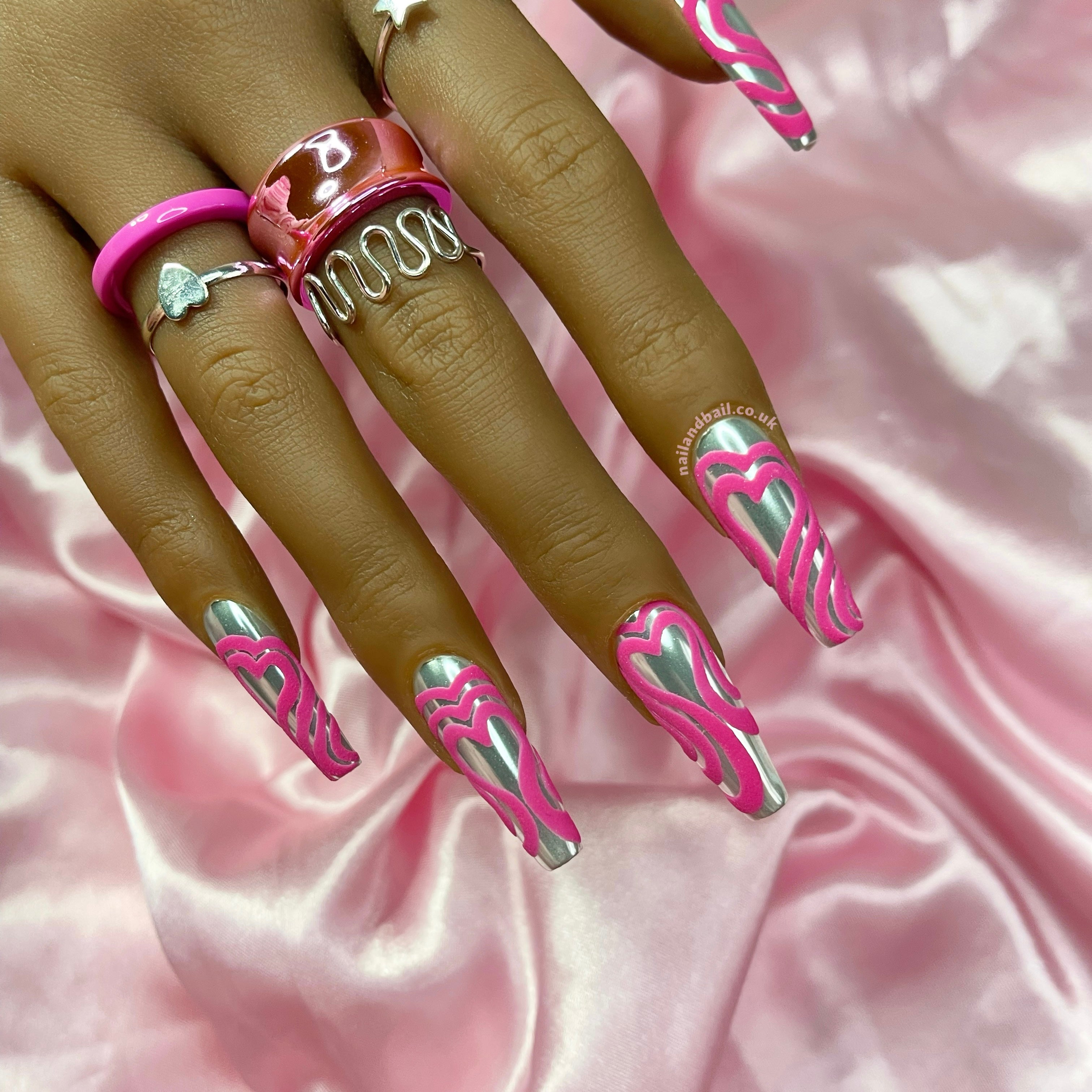 Glossy silver chrome press-on nails with embossed pink heart details