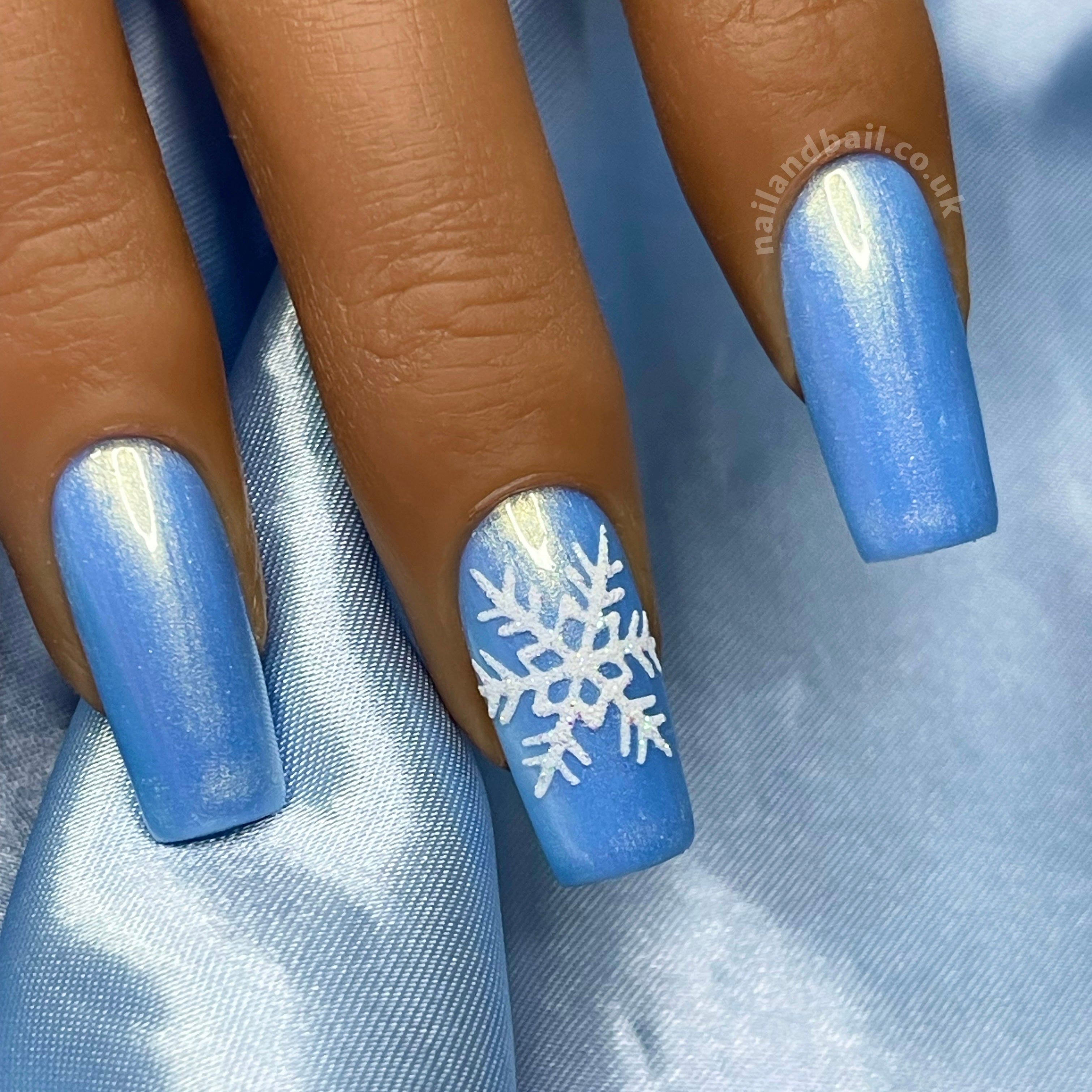 White snowflake nail art on light blue shimmer winter press-on nails