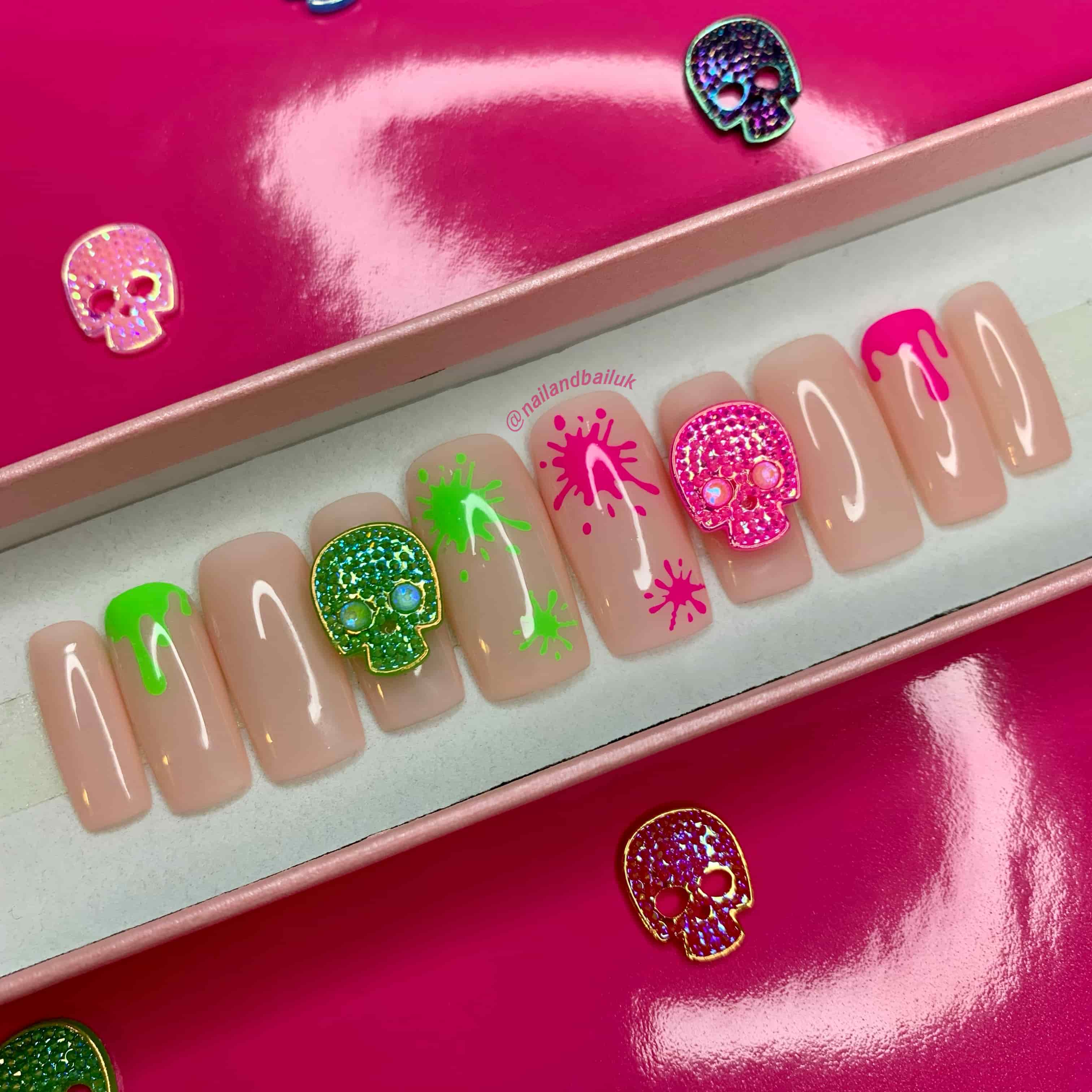 press on nails with pink and green skull designs.