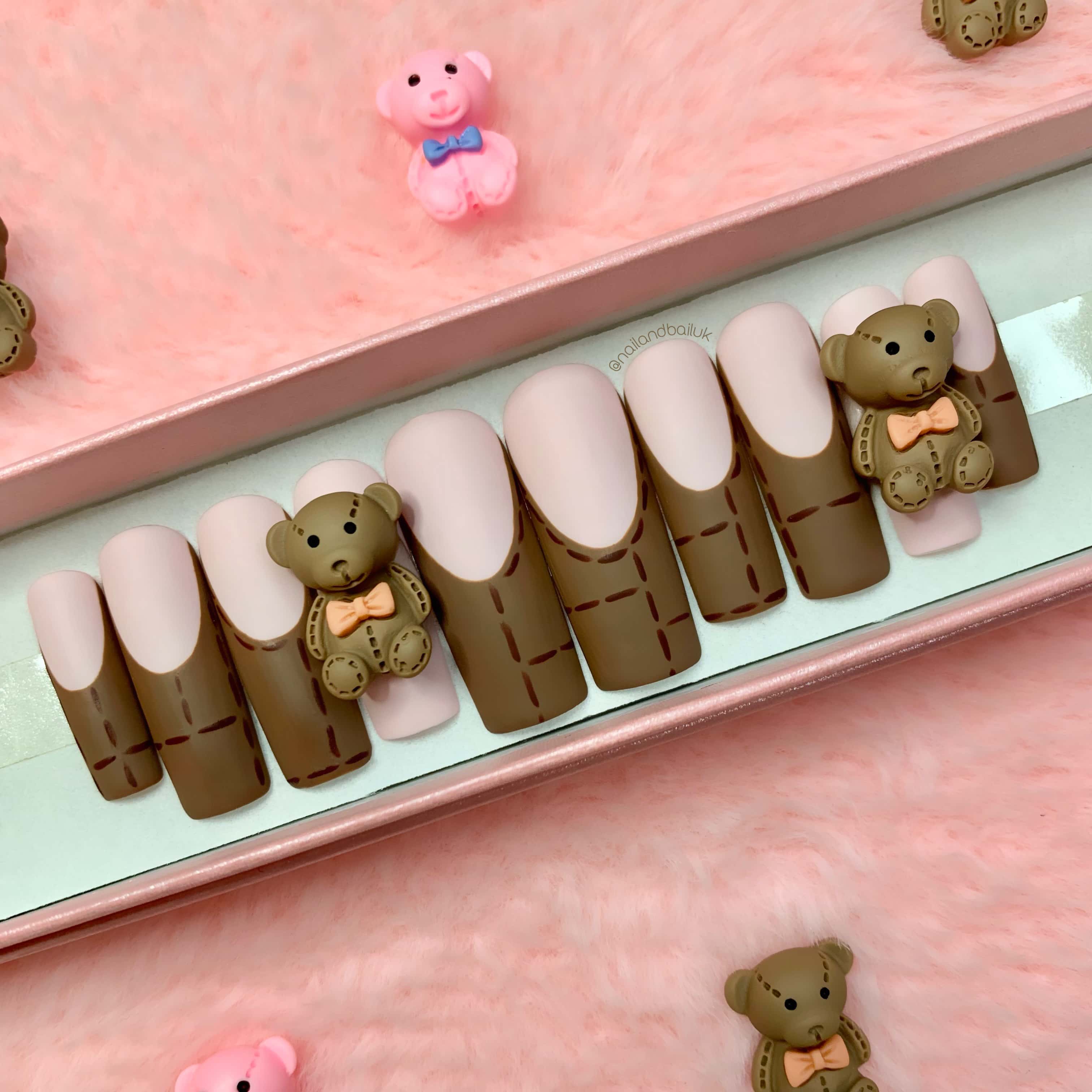 Brown French tip press-on nails with hand-painted stitch details and teddy bear nail charms