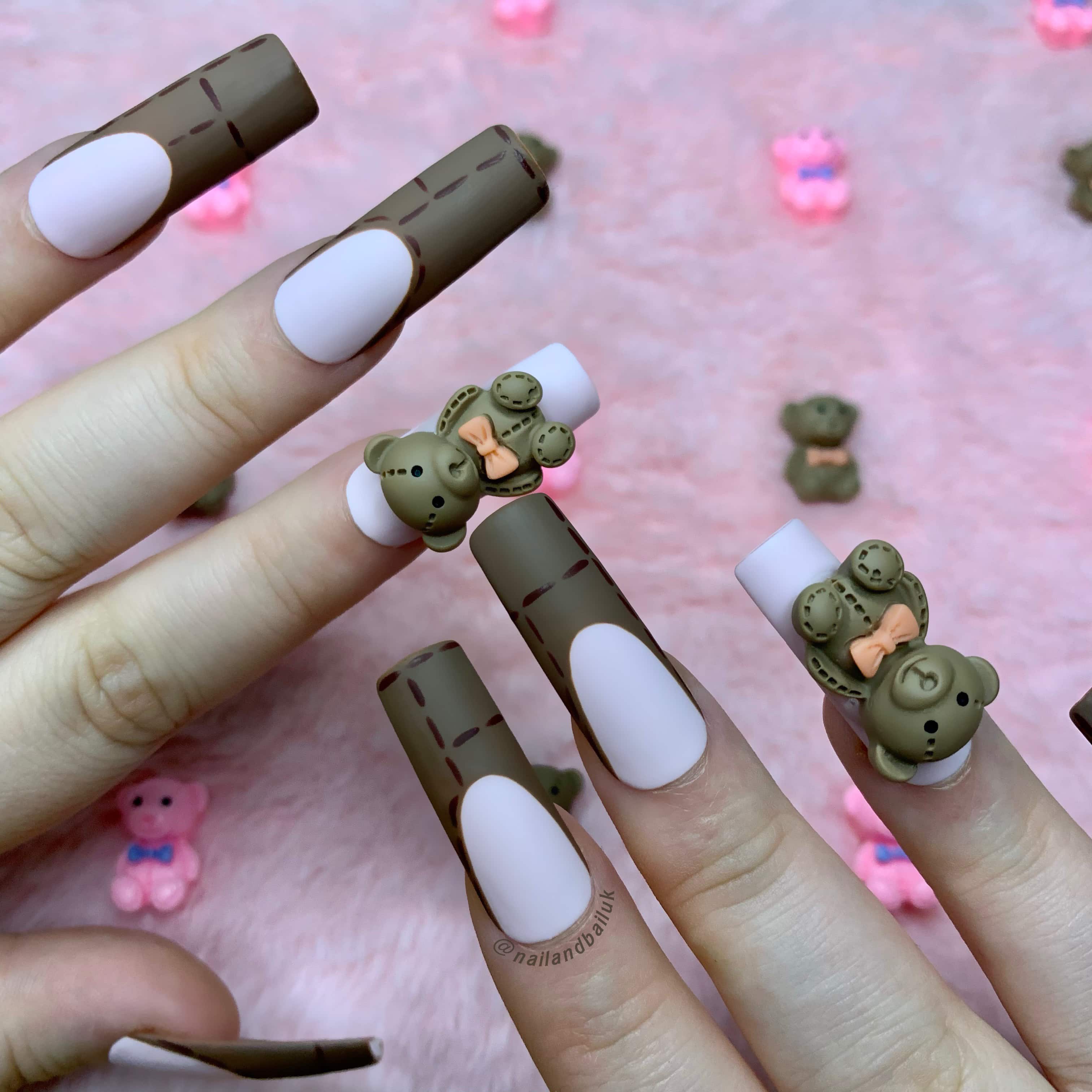 Nude press-on nails with brown French tips, stitch detailing, and 3D teddy bear charms