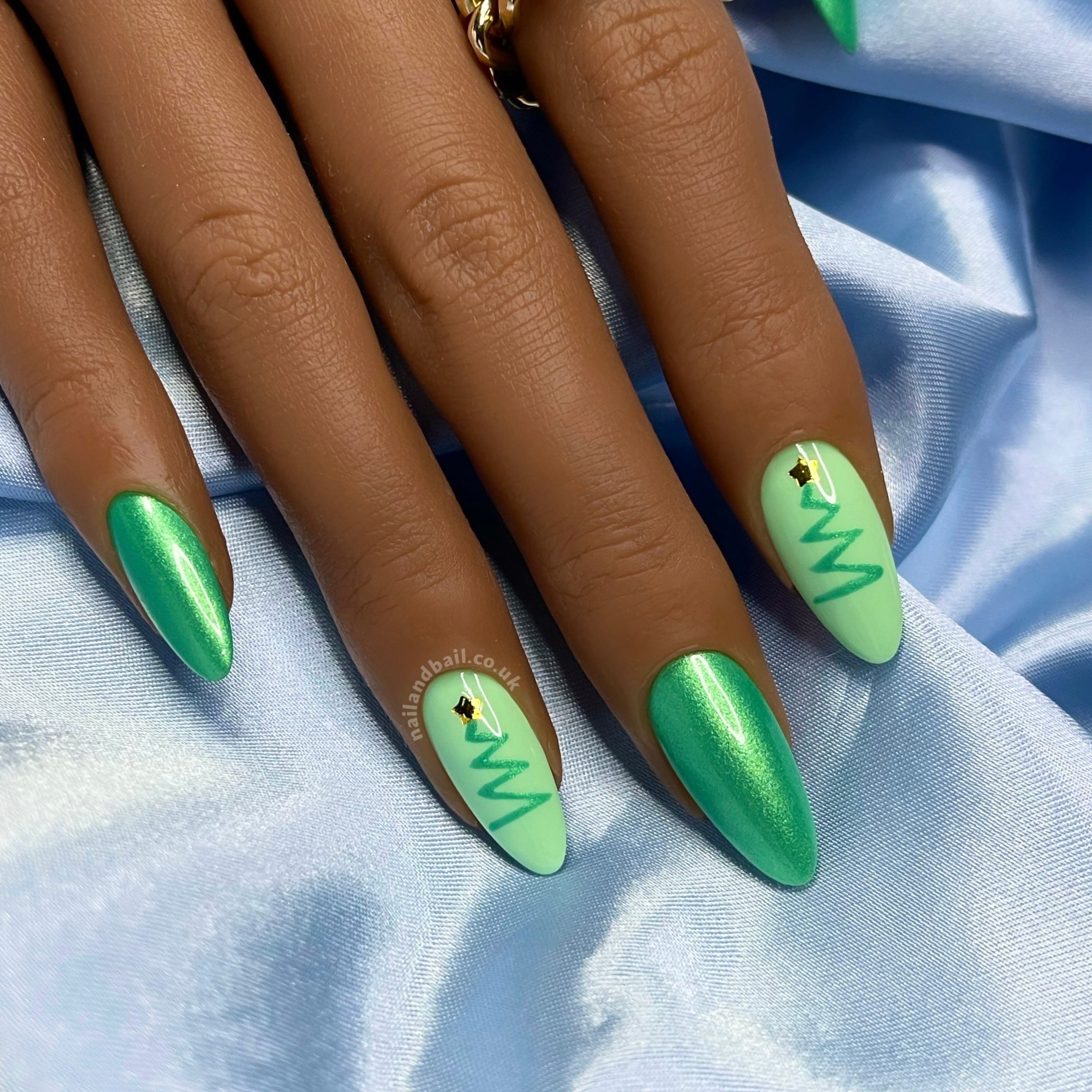 Green shimmer Christmas press-on nails with hand-painted Christmas tree nail art and gold star details