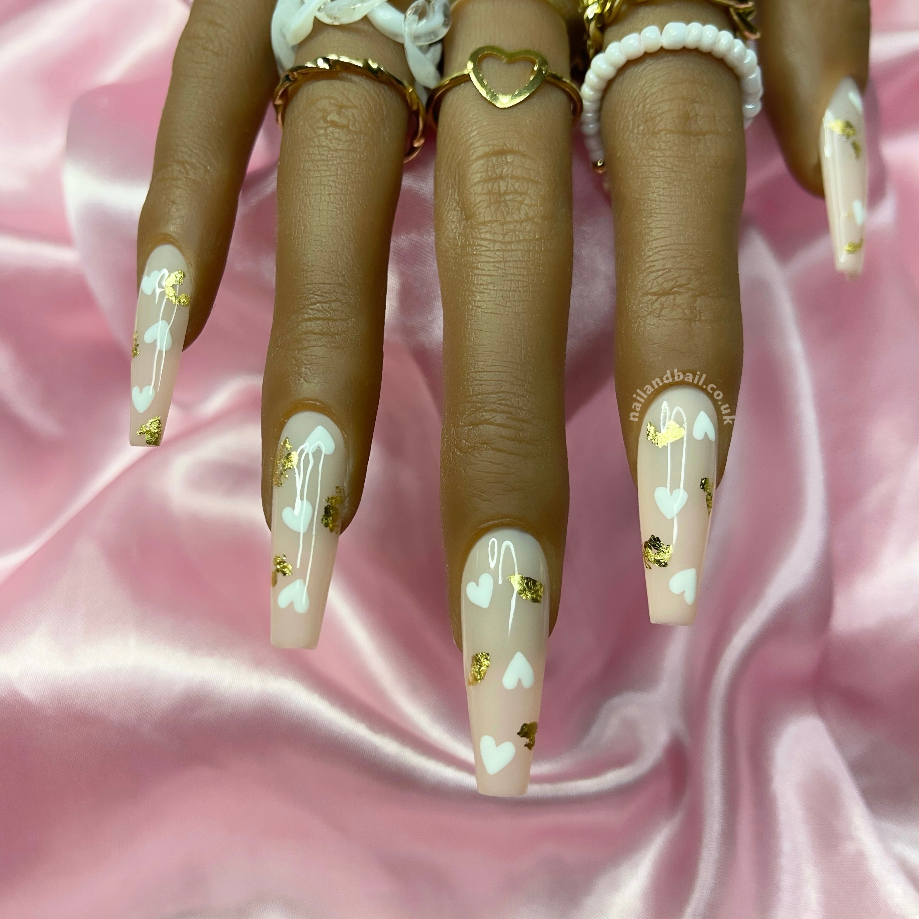 Hand-painted white heart nail art on elegant nude press-on nails