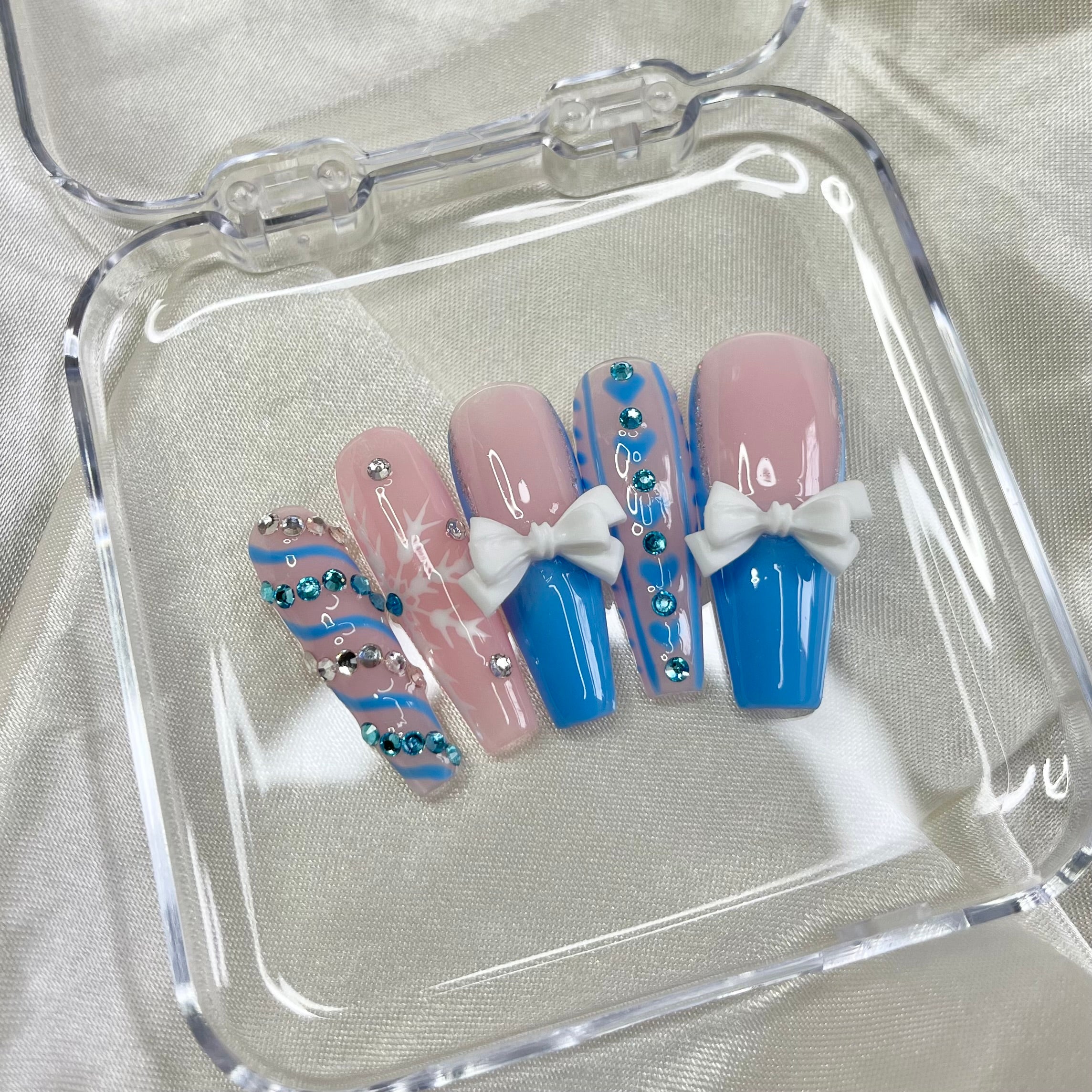 Snowflake nail art with blue crystals on winter-themed press-on nails