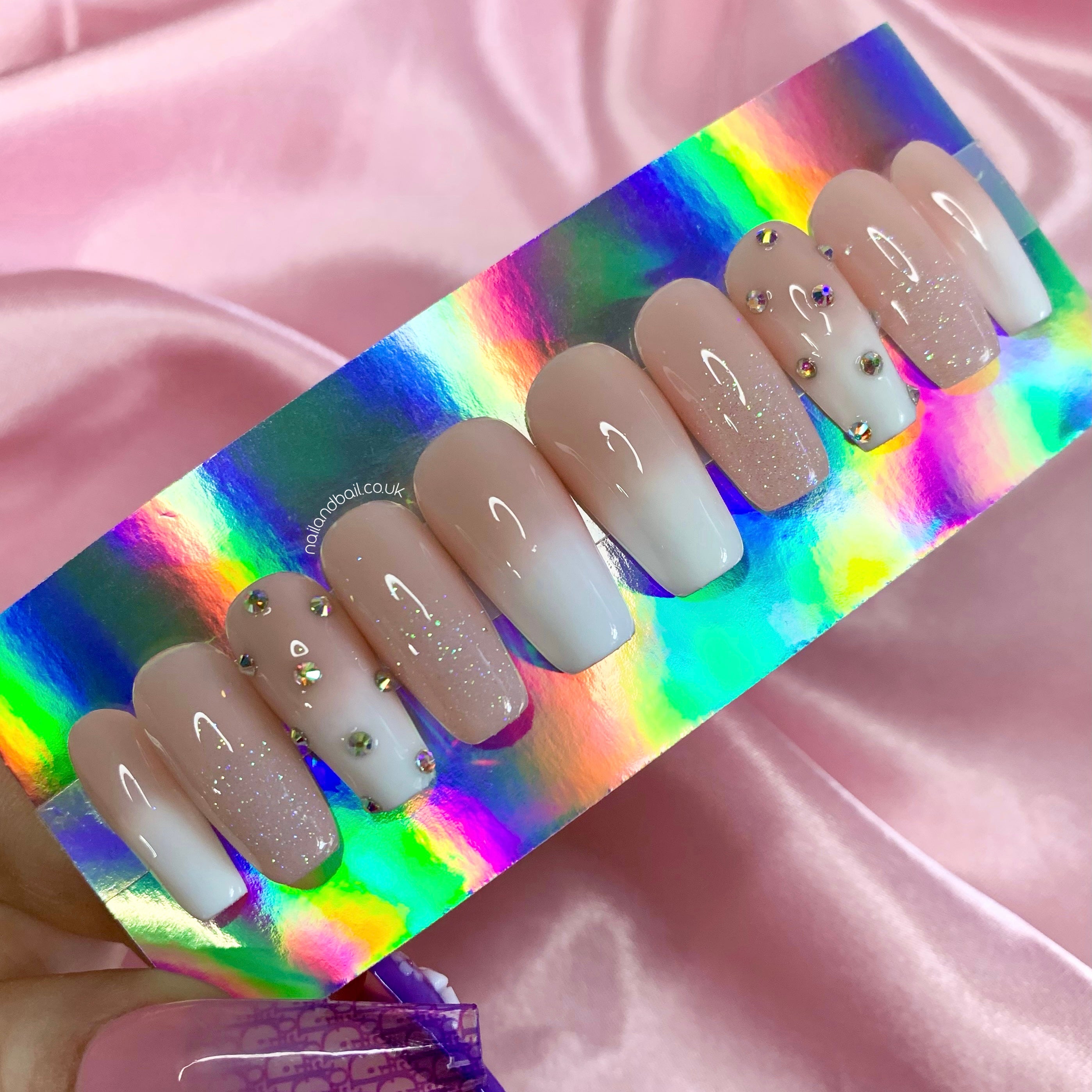 Nude and white ombré press-on nails with glitter fades and silver crystal details