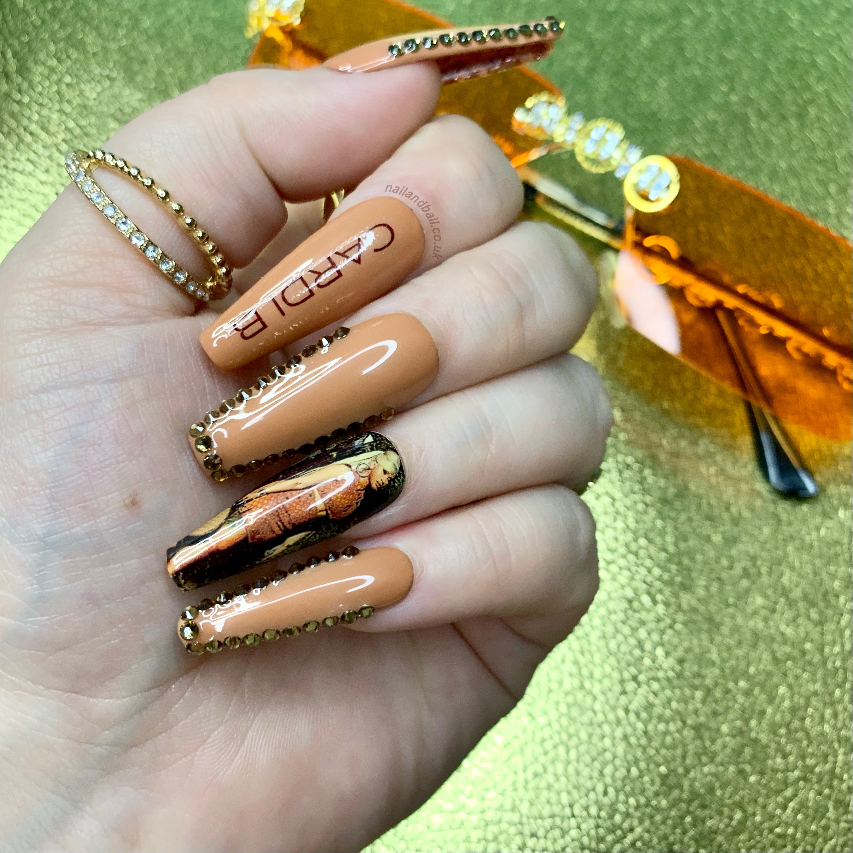 Brown glitter press-on nails with Cardi B-inspired nail art, brown crystal embellishments, and hidden luxury-inspired detailing