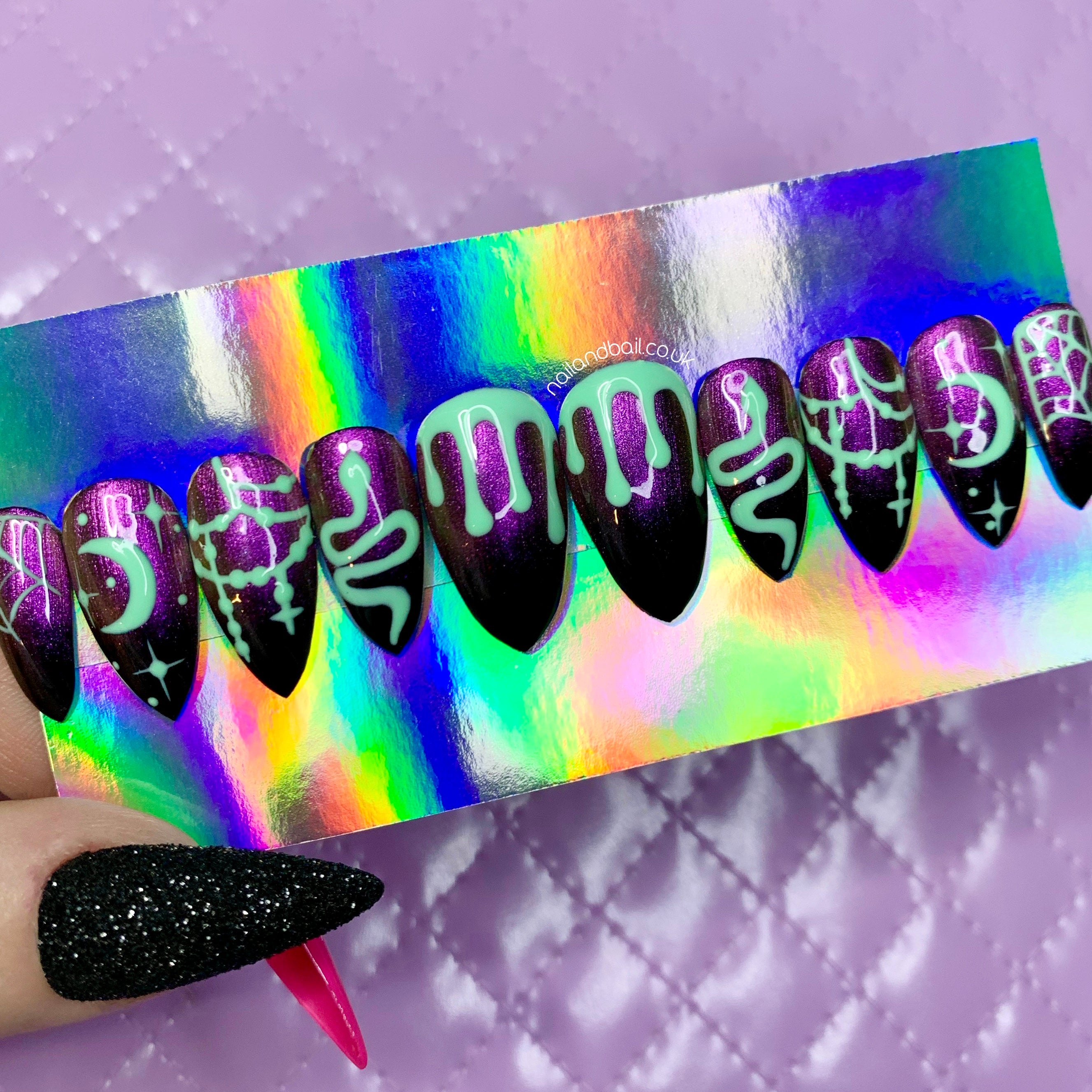 Black and purple cat eye Halloween press-on nails with green slime, snakes, moons, stars, and spiderweb nail art