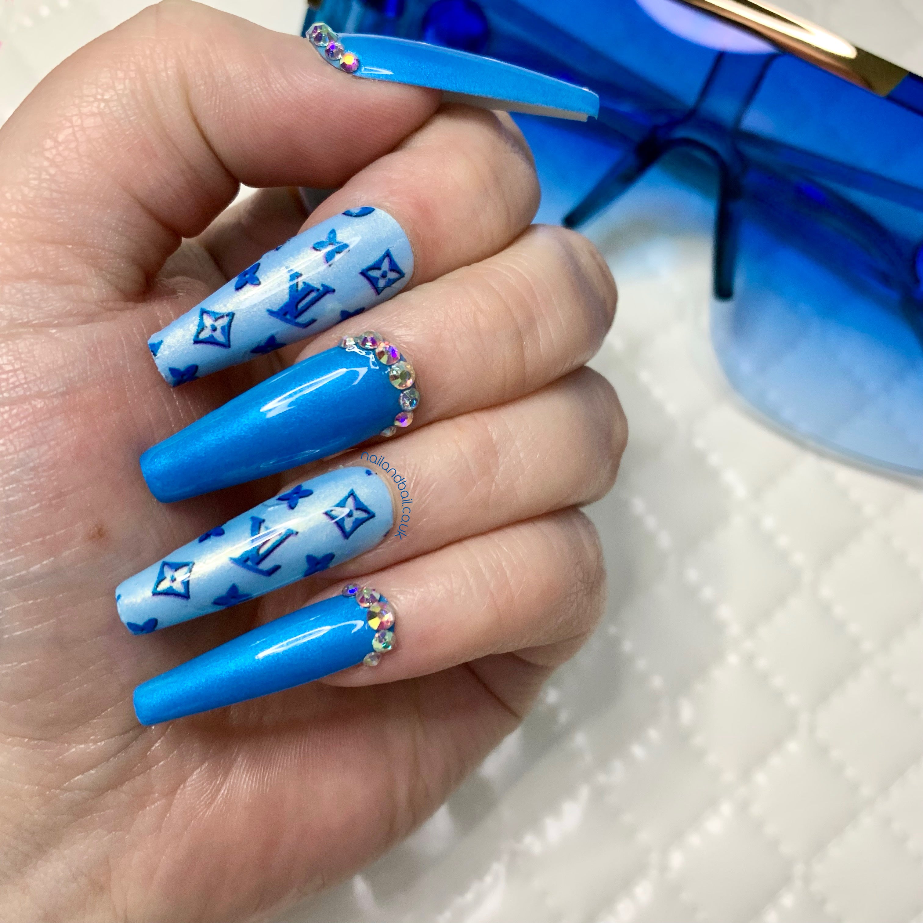 Dark blue shimmer press-on nails with crystal cuticle details and luxury-inspired nail art