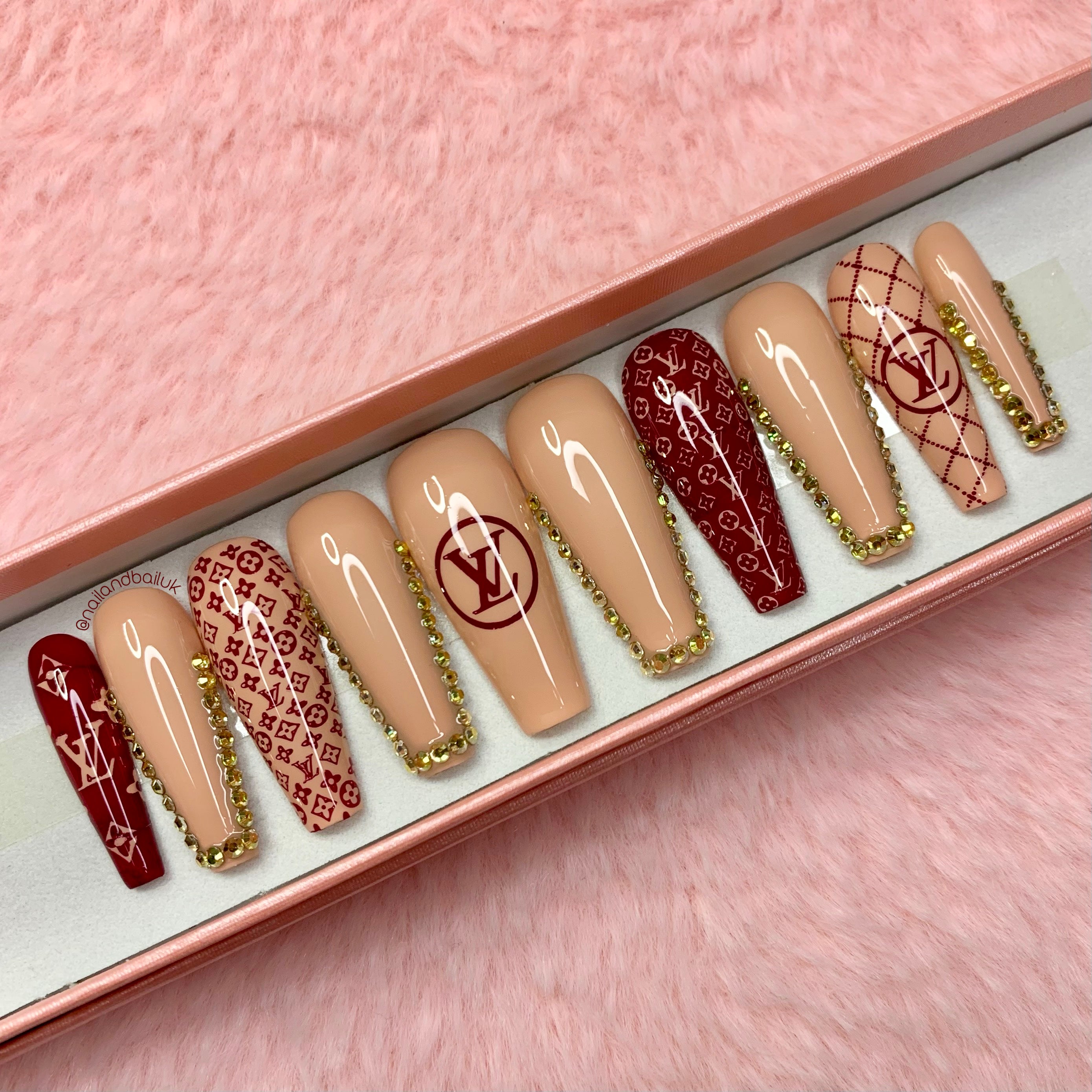 Burgundy press-on nails with luxury-inspired detailing and gold crystal embellishments