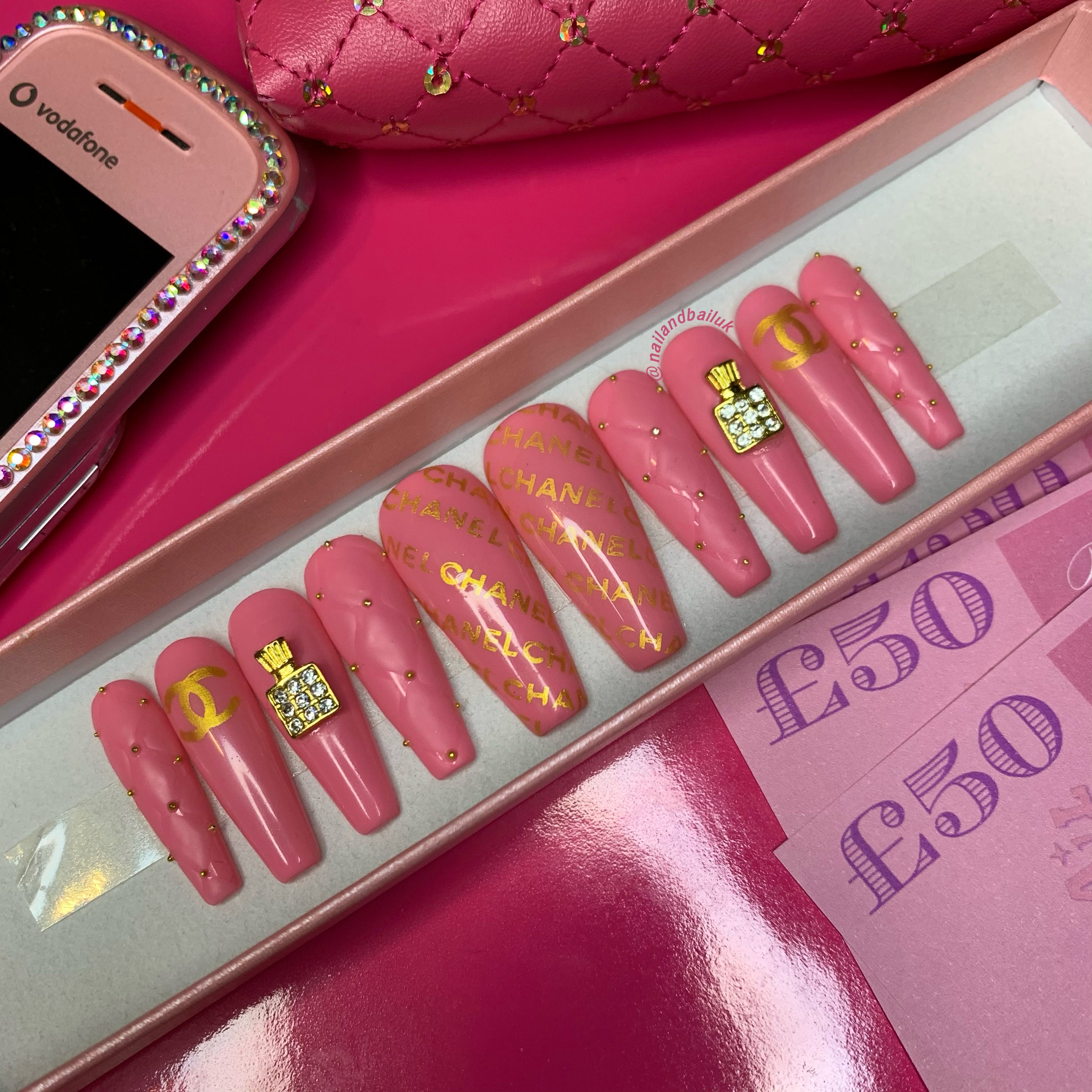 Pink press-on nails with quilted nail art, gold accents, perfume bottle charms, and bead embellishments