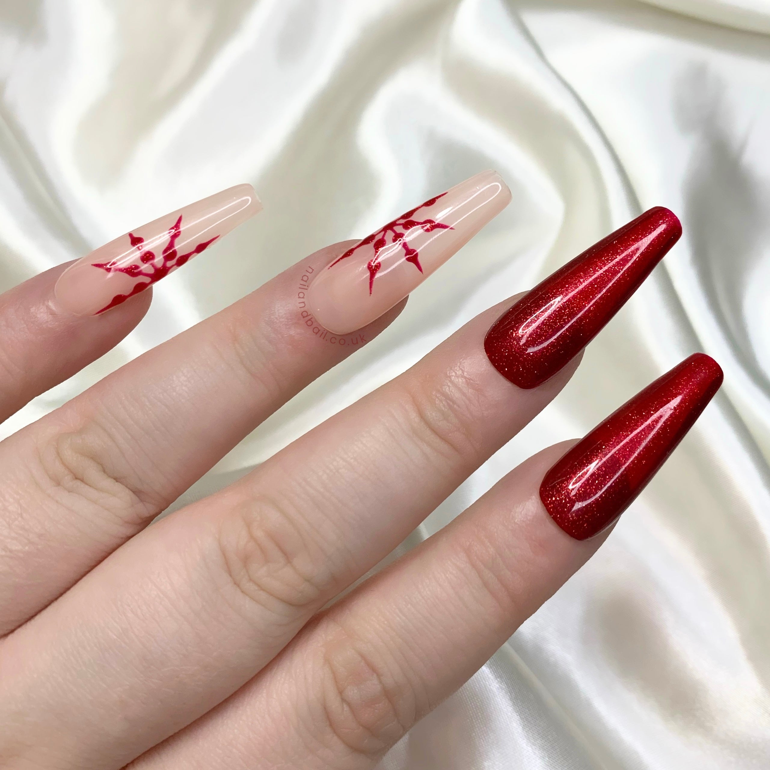 Deep red glitter Christmas press-on nails with connecting snowflake nail art and nude winter details
