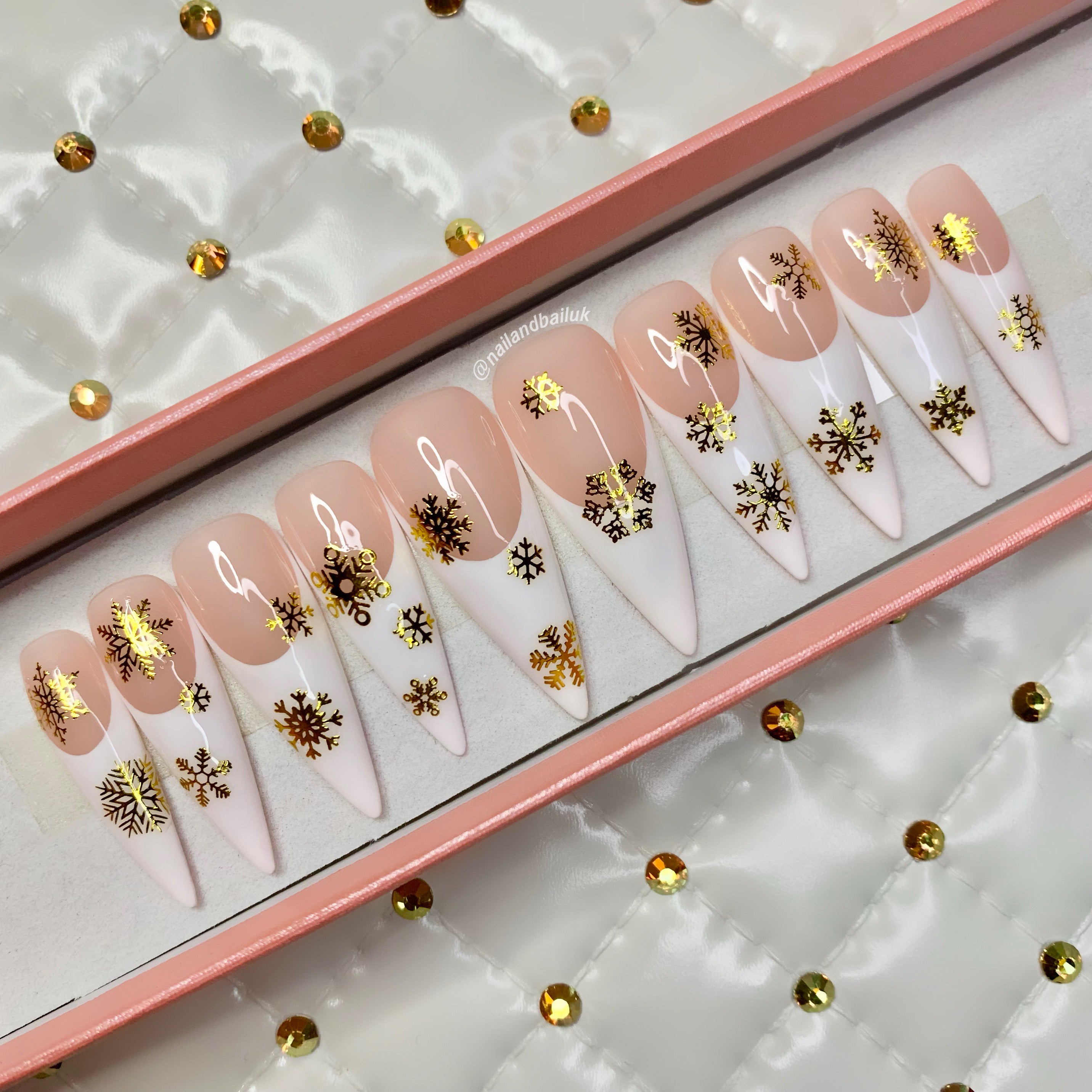 Festive press-on nails with glossy French tips and gold snowflake accents
