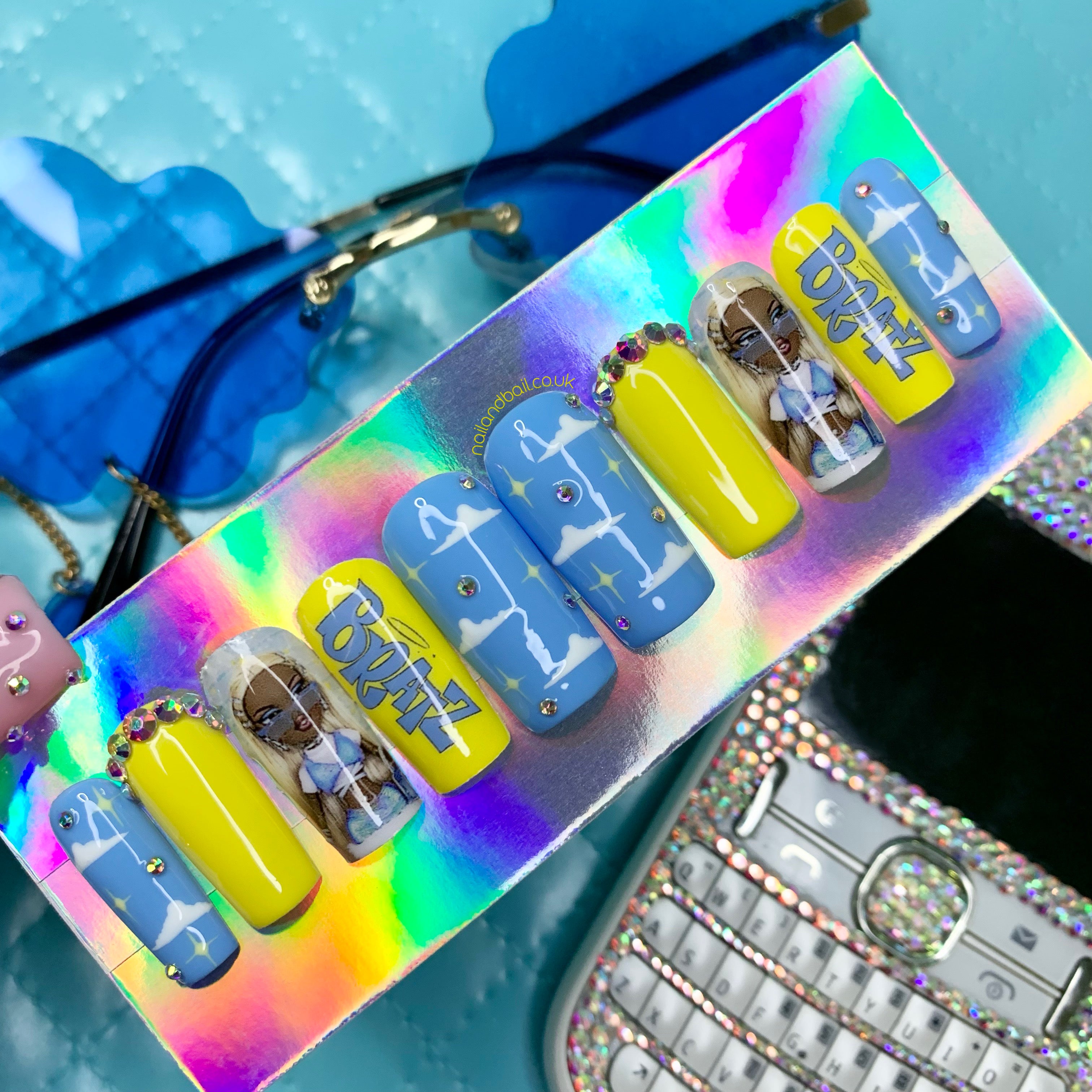 Blue and yellow Y2K press-on nails with cloud nail art, Bratz-inspired details, and crystal accents