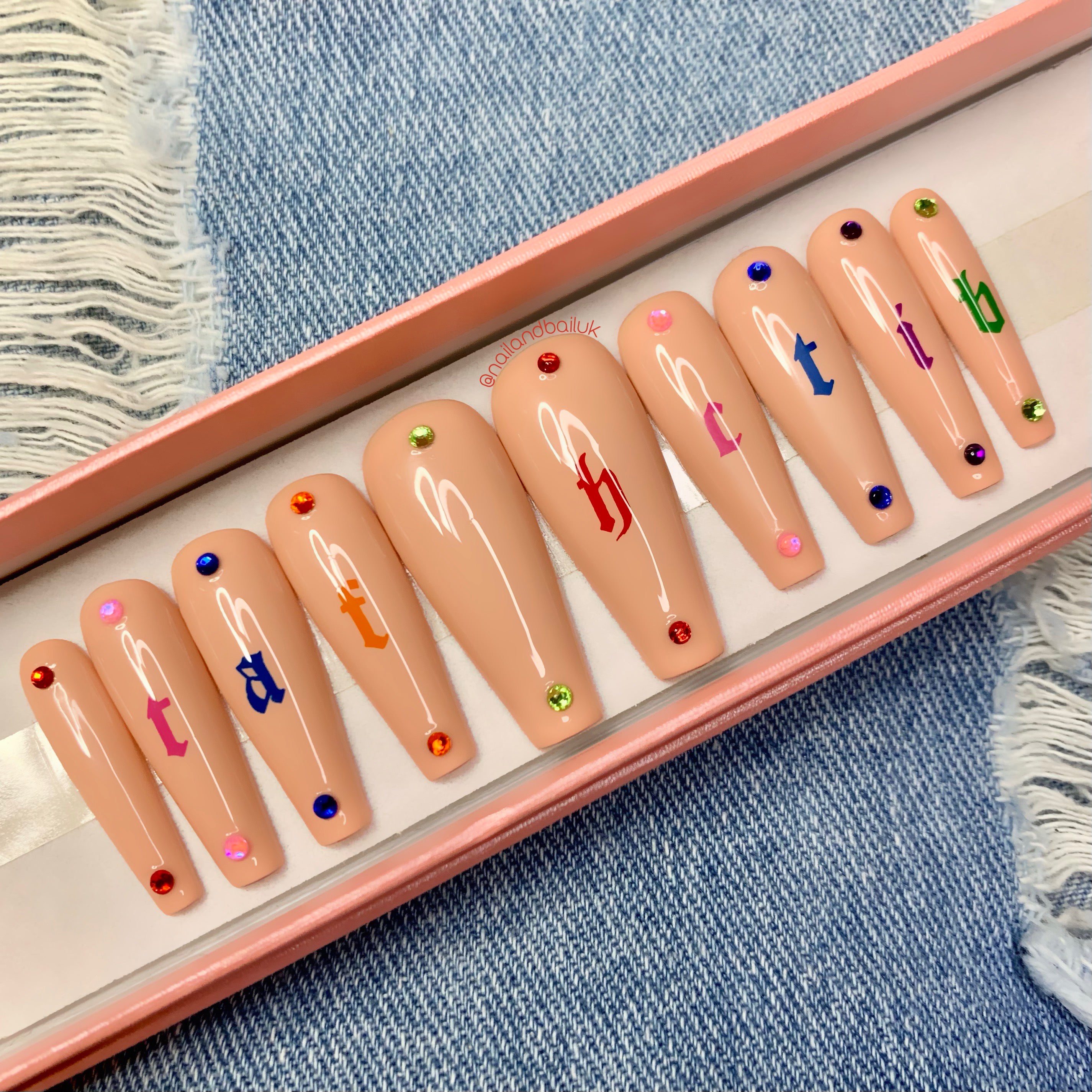 Nude press-on nails with multicoloured statement lettering and sparkling crystal details