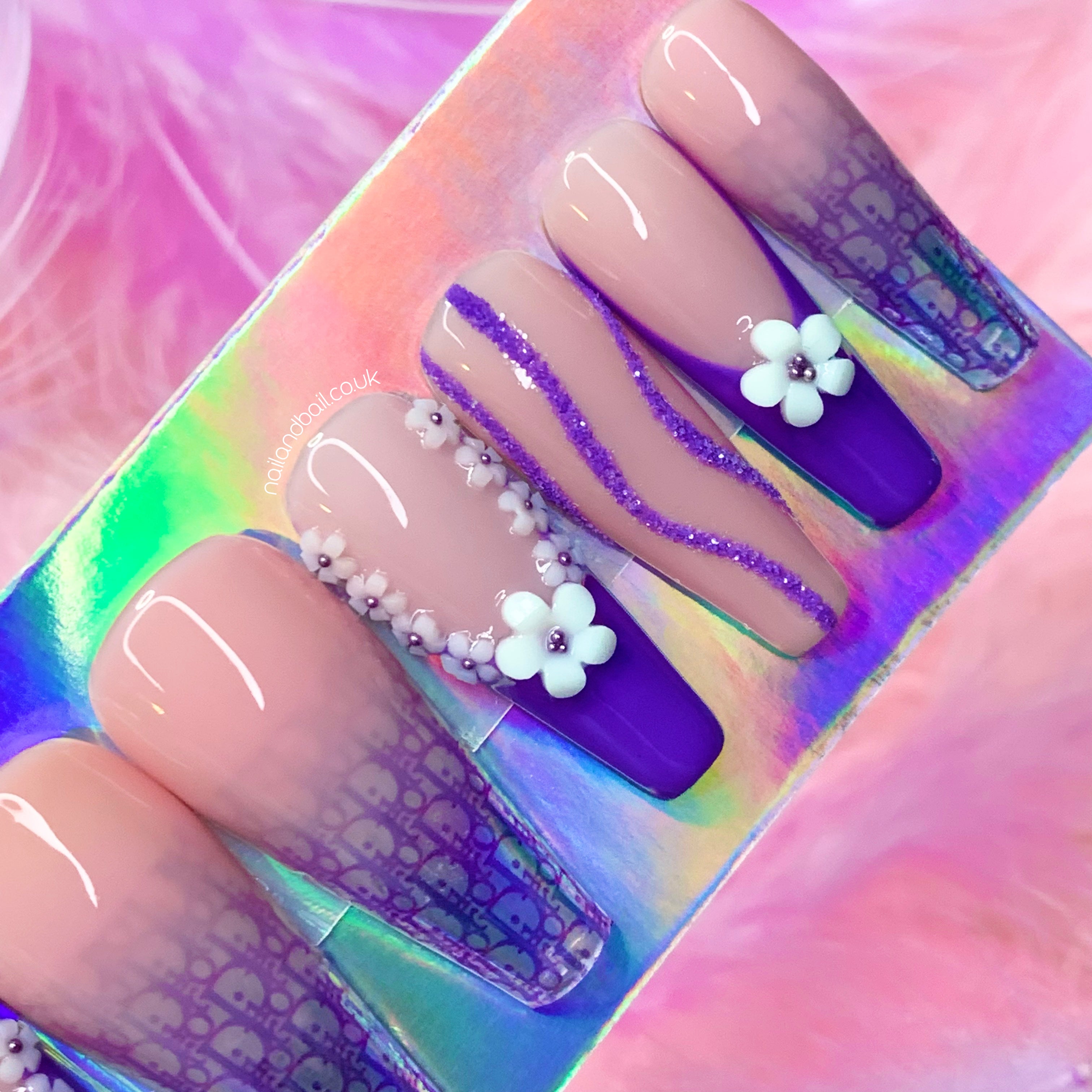 White flower charm nail art with dark purple bead centres on glam press-on nails