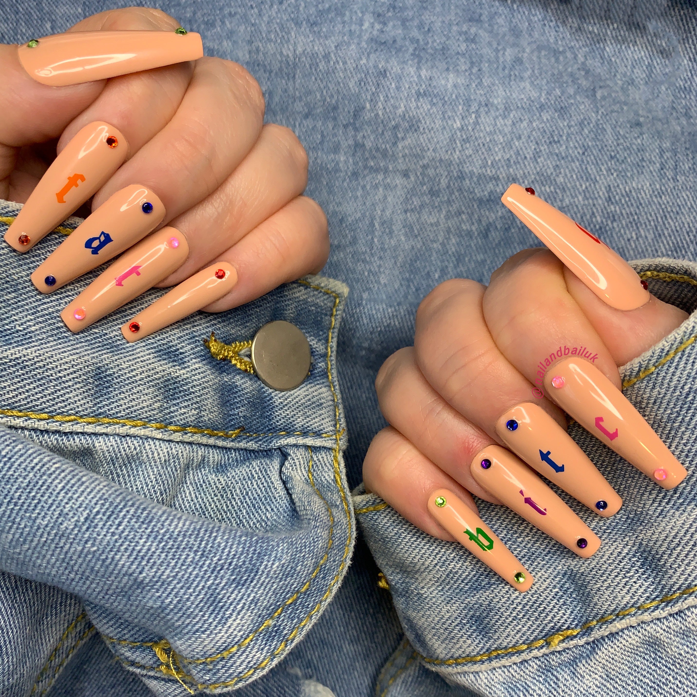 Nude press-on nails with colourful lettering, crystal embellishments, and glossy finish
