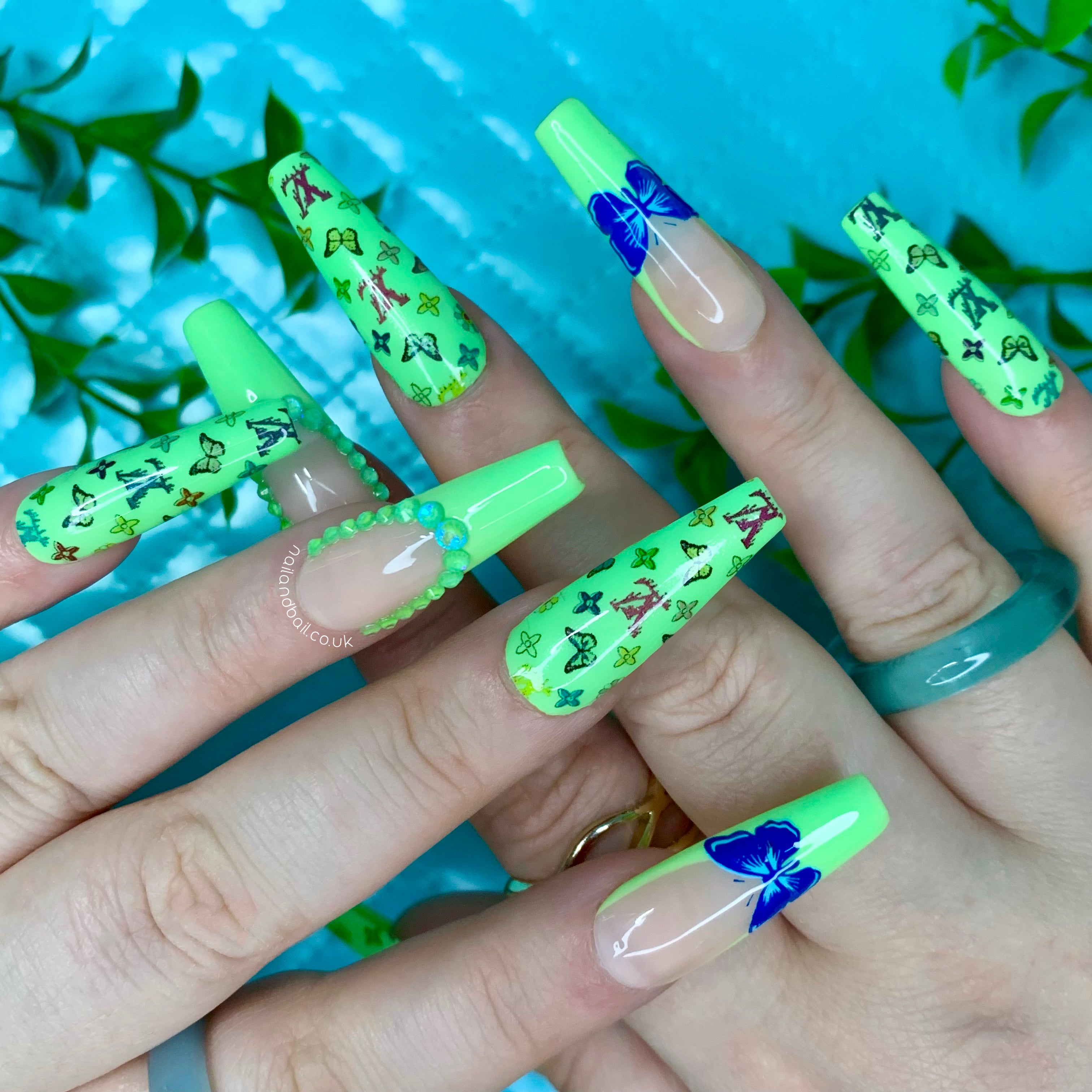 Light green press-on nails with butterfly nail art, floral details, green French tips, and crystal accents