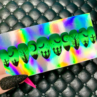 Green ombré Halloween press-on nails with graveyard silhouette nail art, bats, crosses, and matte finish