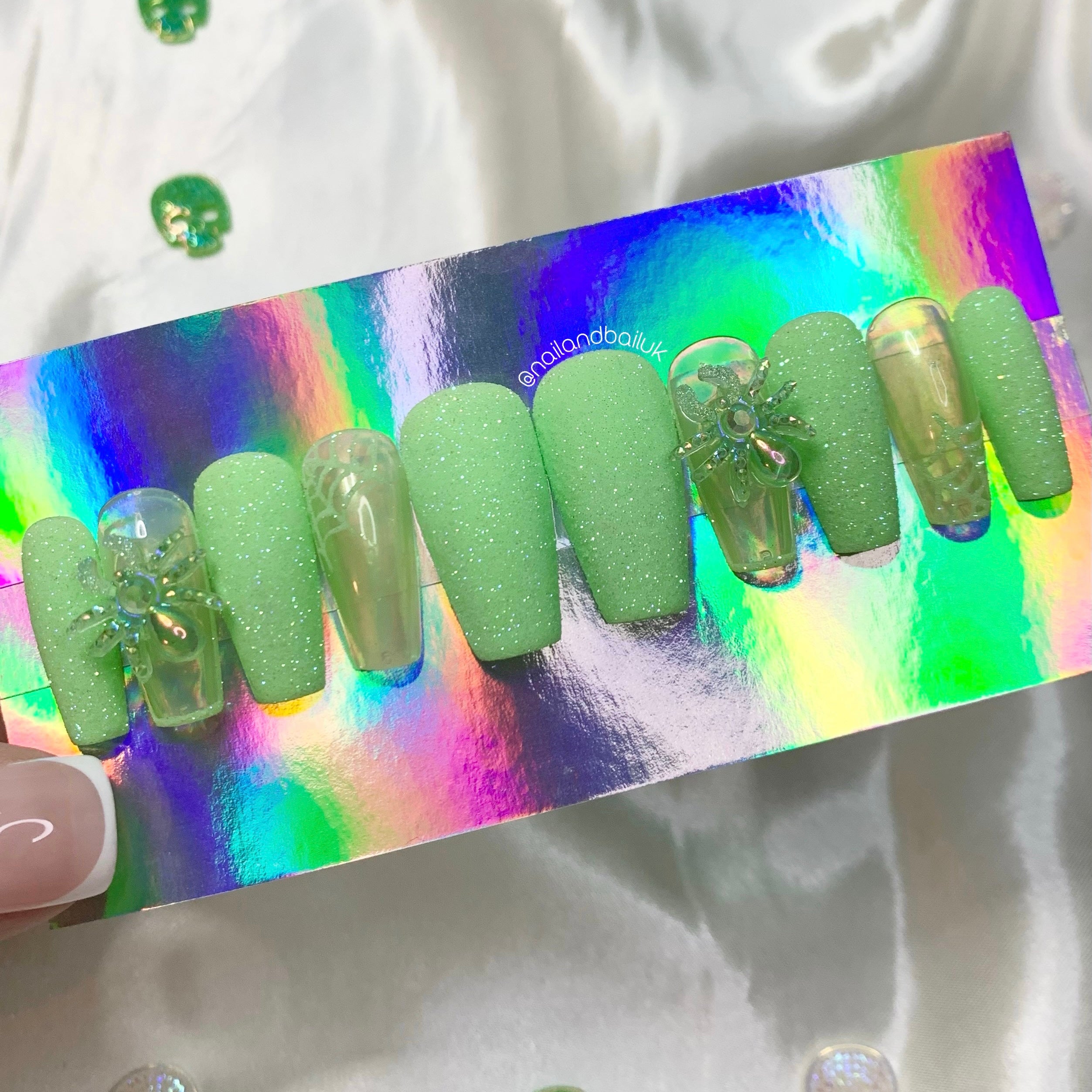 Green sugared glitter spiderweb nail art on iridescent Halloween press-on nails